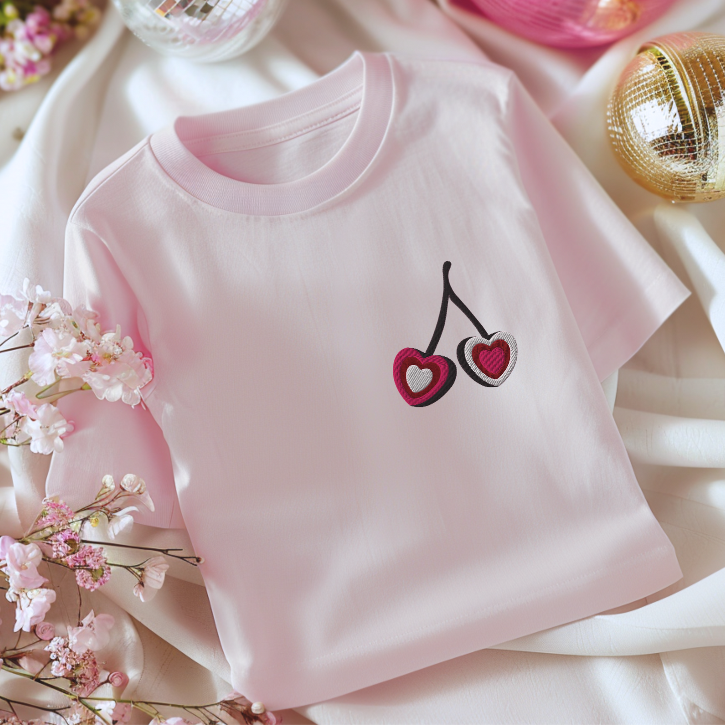 Image: A trendy cherry embroidered sweatshirt featuring a sweet fruit motif with a delicate bow, blending coquette charm with casual comfort. This cherry heart tee is perfect for those who love cute and minimalist designs. A versatile piece for layering or wearing solo, it adds a feminine touch to any look. Whether shopping for a loved one or updating your own collection, this embroidered shirt is a must-have, by jaecrece.