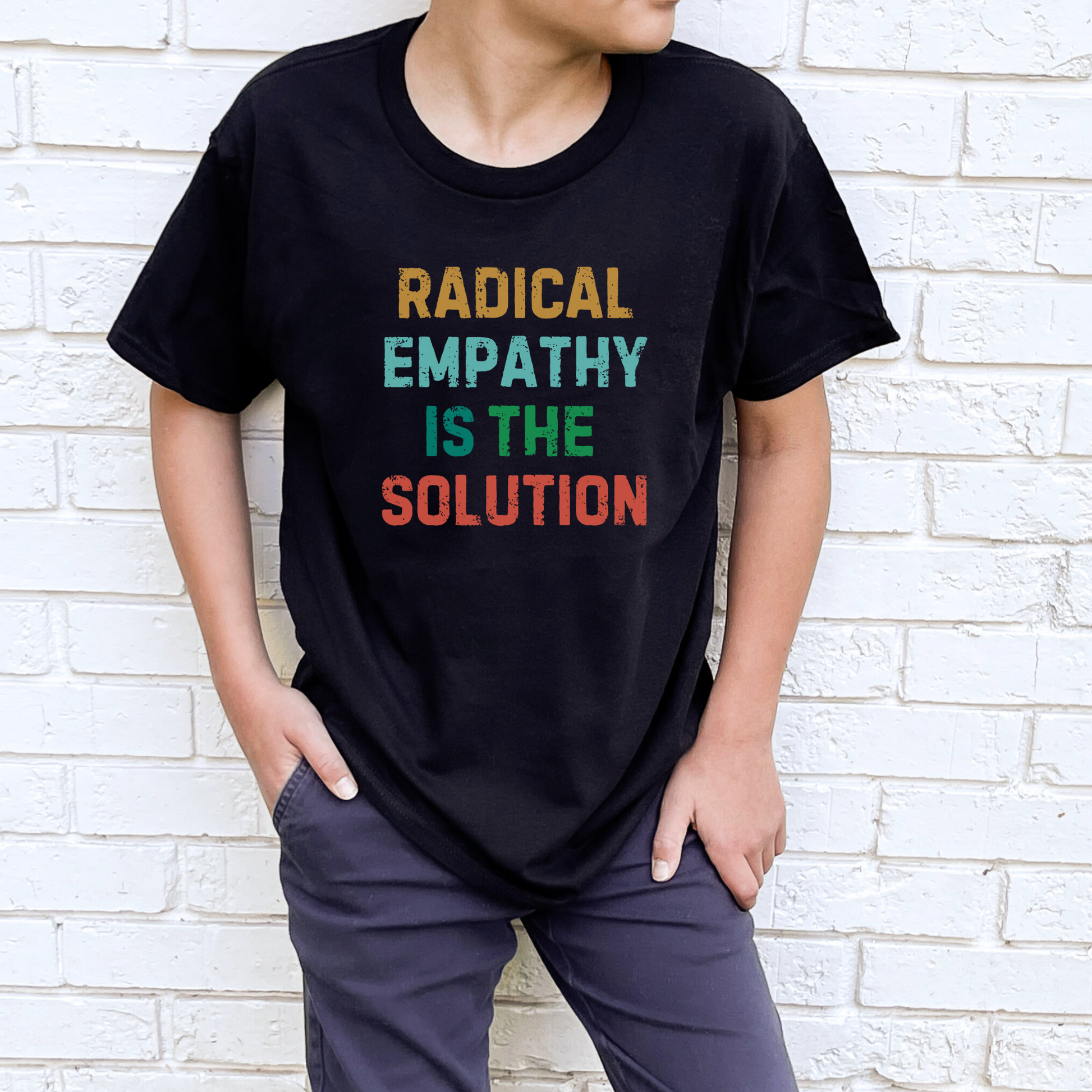Image: A youth-sized t-shirt with the phrase "Radical Empathy is the Solution" printed boldly across the chest, designed for kids who believe in kindness and inclusion. This activist-inspired shirt makes a great statement piece for young change-makers who want to promote compassion. Perfect for boys and girls who support mental health awareness and social justice, by jaecrece.