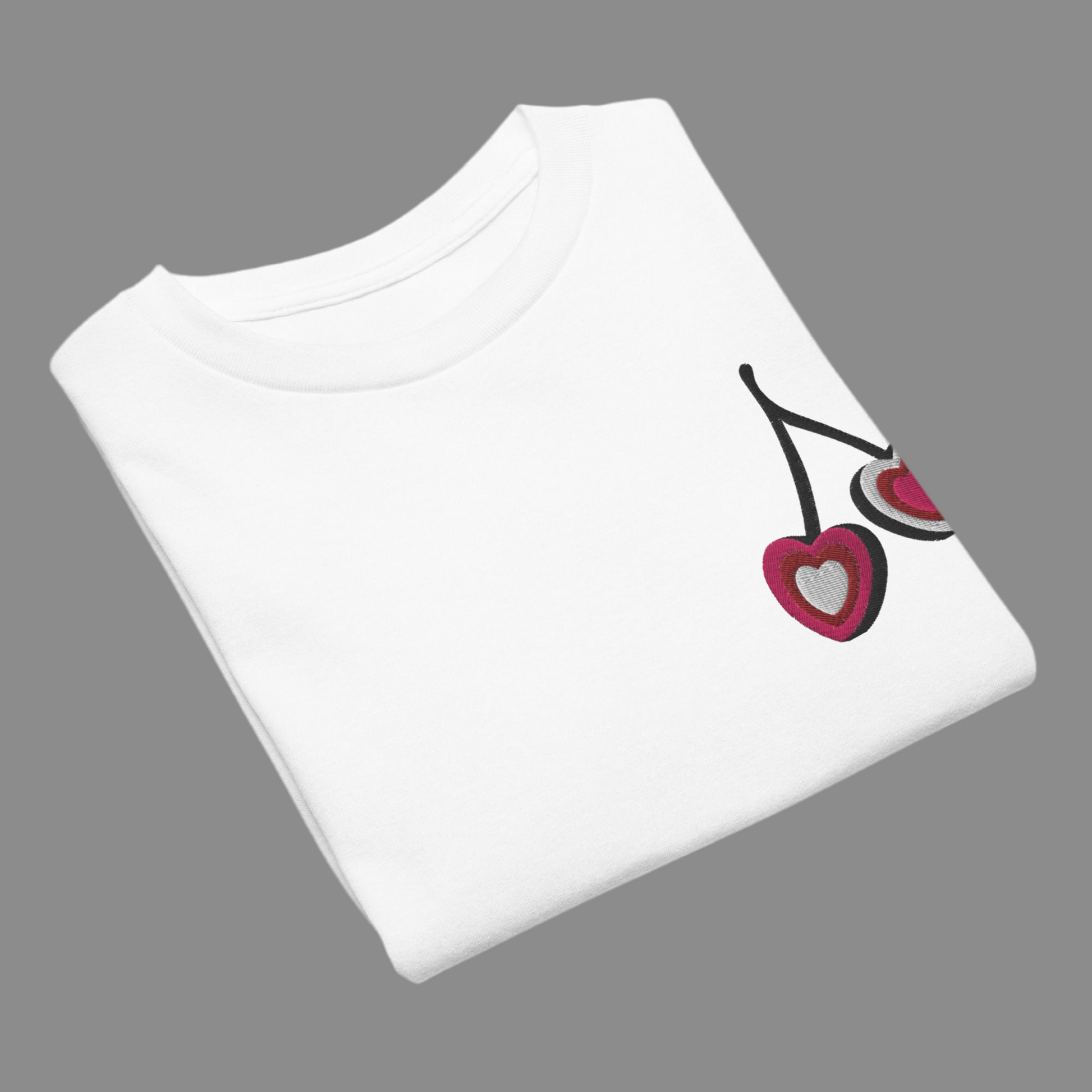 Image: Cherry Embroidery Shirt for Girls. This Valentines Day crewneck tee features two embroidered cherries on the left chest in red, pink and white with black stems. Great gift for tweens and toddlers who love the cherrycore aesthetic, by jaecrece