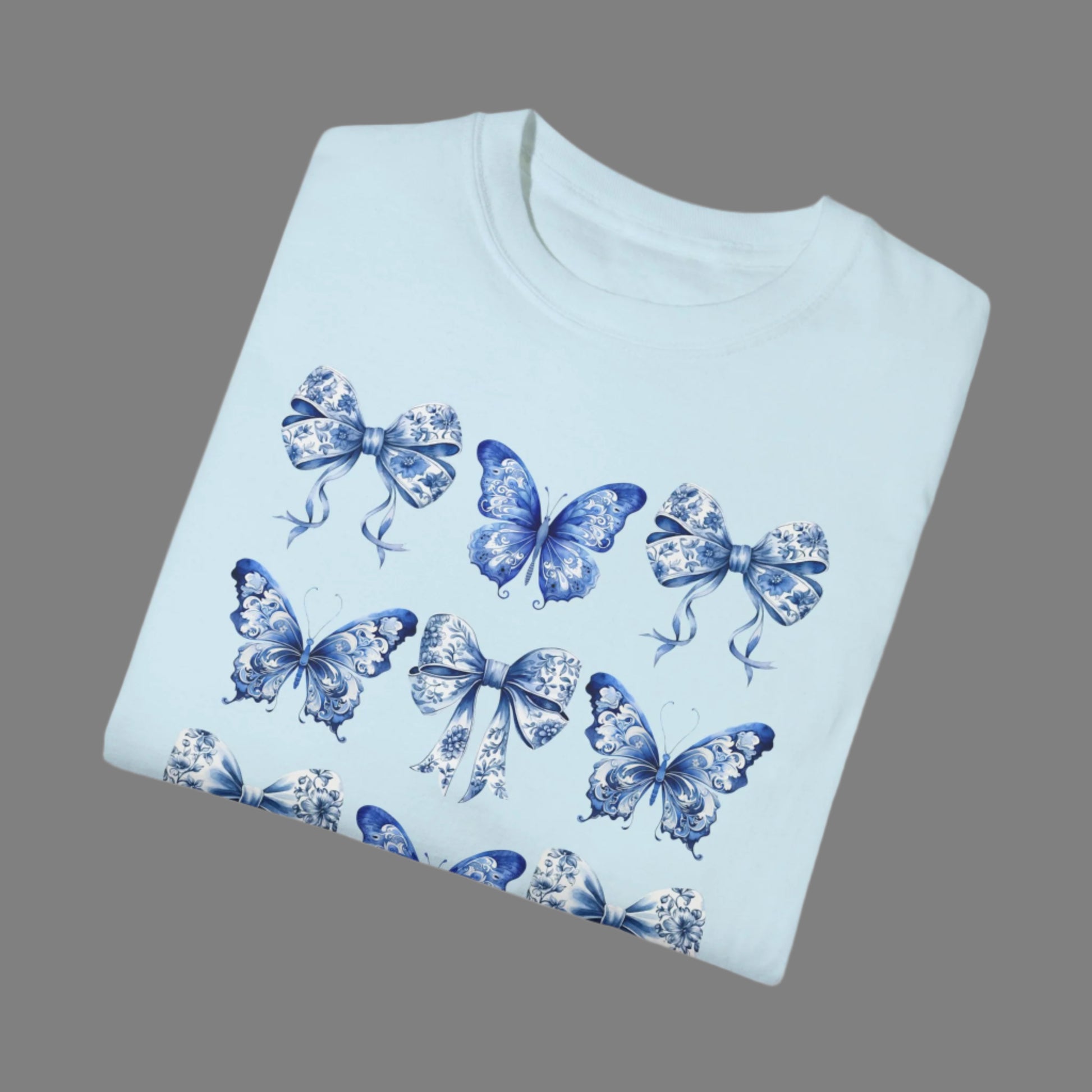 Image: Elegant women’s tee featuring butterflies, blue toile bows, and delicate detailing, capturing both French aesthetic and soft girl charm. Perfect for bougie mamas and cottagecore lovers, this top is designed for comfort and flair. As part of a matching family collection, you can coordinate with toddler and youth sizes for effortlessly stylish family looks during spring outings or photo shoots, by jaecrece.