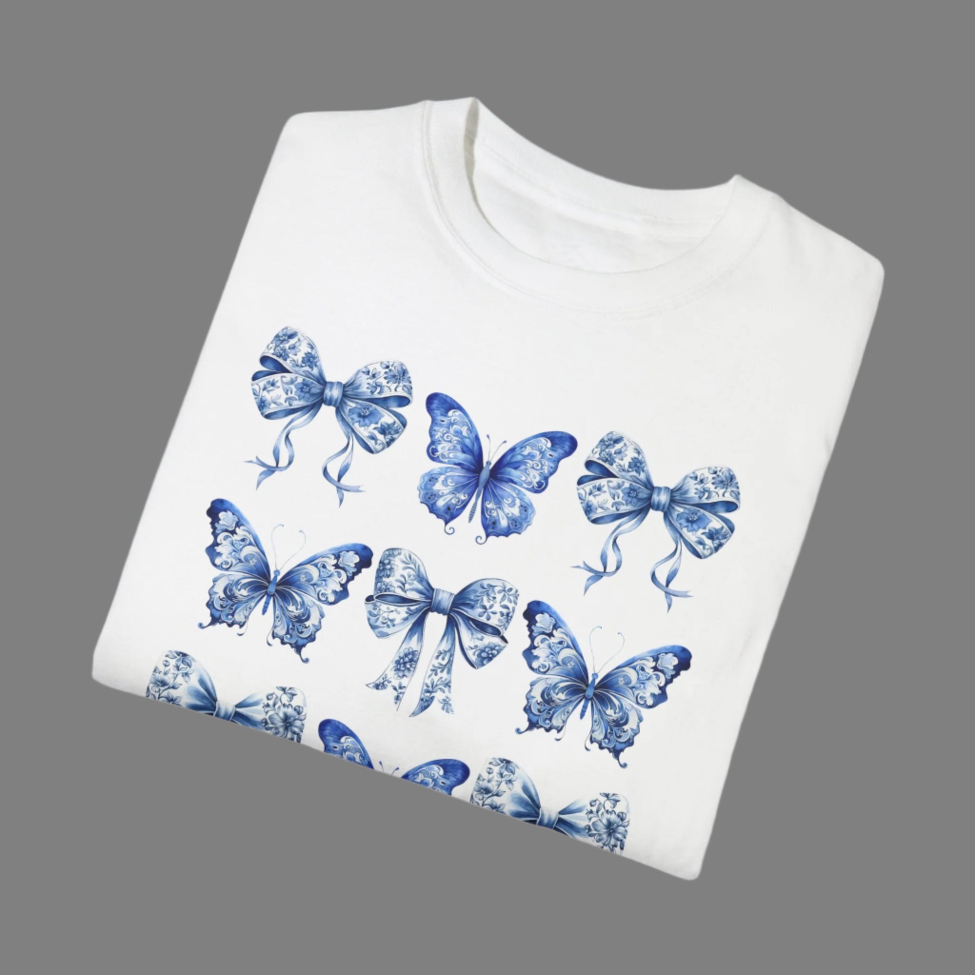 Image: With its dreamy butterfly and bow motif set against a vintage-inspired blue toile background, this women’s shirt blends soft girl style with French country elegance. A staple for bougie mamas and fans of the chinoiserie trend, it’s the perfect tee for family gatherings or spring strolls. Match it with girls’ and toddler sizes for an Instagram-ready mother-daughter look, by jaecrece.