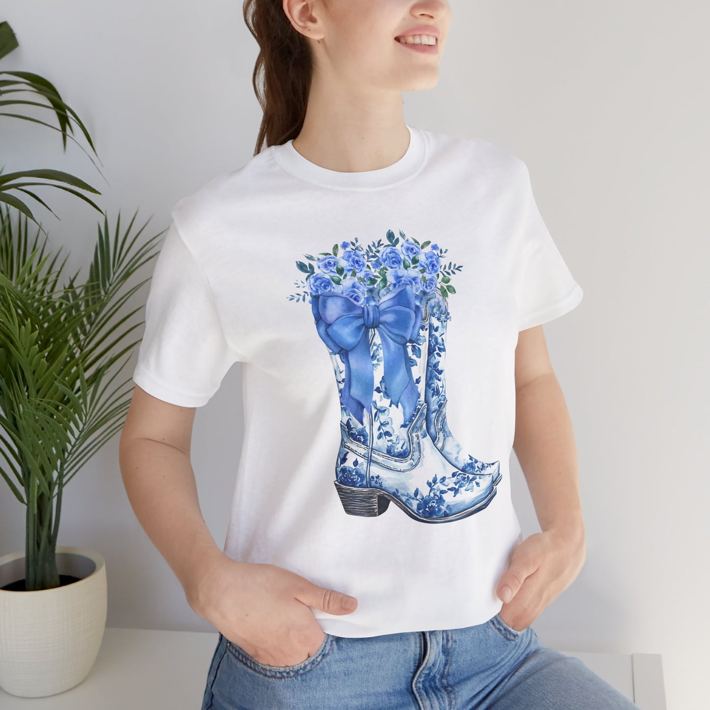 Image: Blue Toile Boots and Bows shirt in sizes for women. This pullover shirt features a pair of coastal cowgirl aesthetic cowboy boots with a blue bow and blue wildflowers. This country themed sweater makes a perfect gift for your daughter, or for the boujee mama in your life, by jaecrece