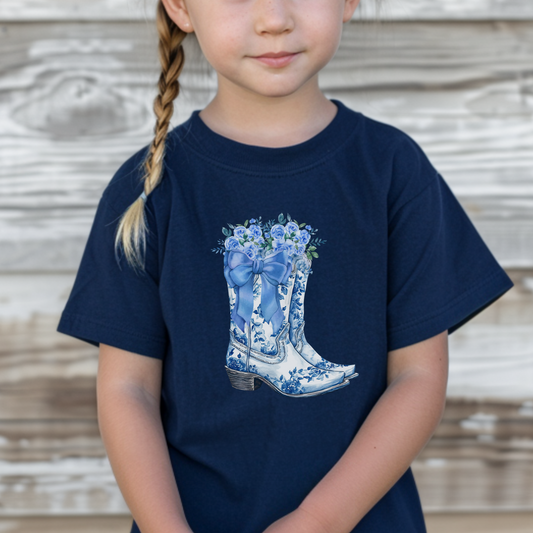 This Blue Toile Floral Cowboy Boots Toddler Tee is perfect for little ones who love western style with a soft girl twist. Featuring a detailed blue toile de jouy pattern and chic cowgirl boots, this toddler graphic shirt blends classic French aesthetic with Texas charm. Ideal for rodeo days, Western-themed parties, or everyday adventures. A must-have for fans of bougie mama style, blue toile fashion, and toddler western outfits.