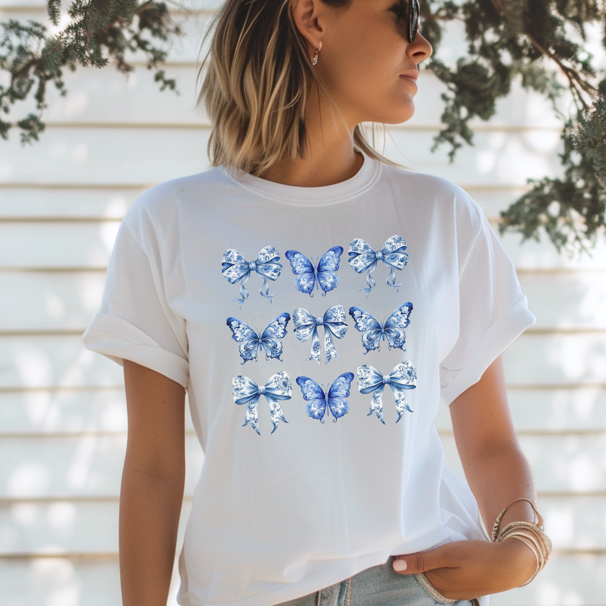 Image: With its dreamy butterfly and bow motif set against a vintage-inspired blue toile background, this women’s shirt blends soft girl style with French country elegance. A staple for bougie mamas and fans of the chinoiserie trend, it’s the perfect tee for family gatherings or spring strolls. Match it with girls’ and toddler sizes for an Instagram-ready mother-daughter look, by jaecrece.
