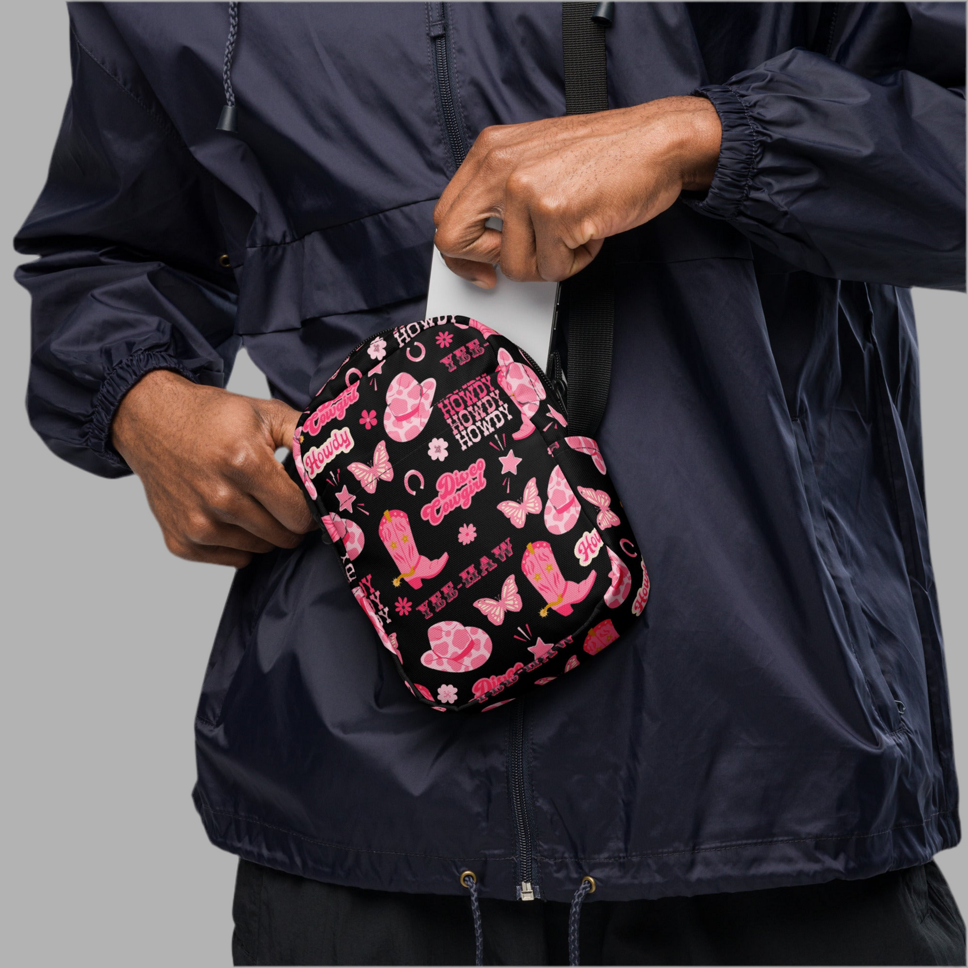 Image: Disco Cowgirl Canvas Crossbody Bag. This small black sling bag features a western glam hot pink pattern of cowgirl boots, cowgirl hats, butterflies and horseshoes. The pattern reads Disco Cowgirl, Yee-Haw and Howdy. The perfect mini backpack for bachelorette parties, gifts for teens or tweens, or trips to the state fair, by jaecrece