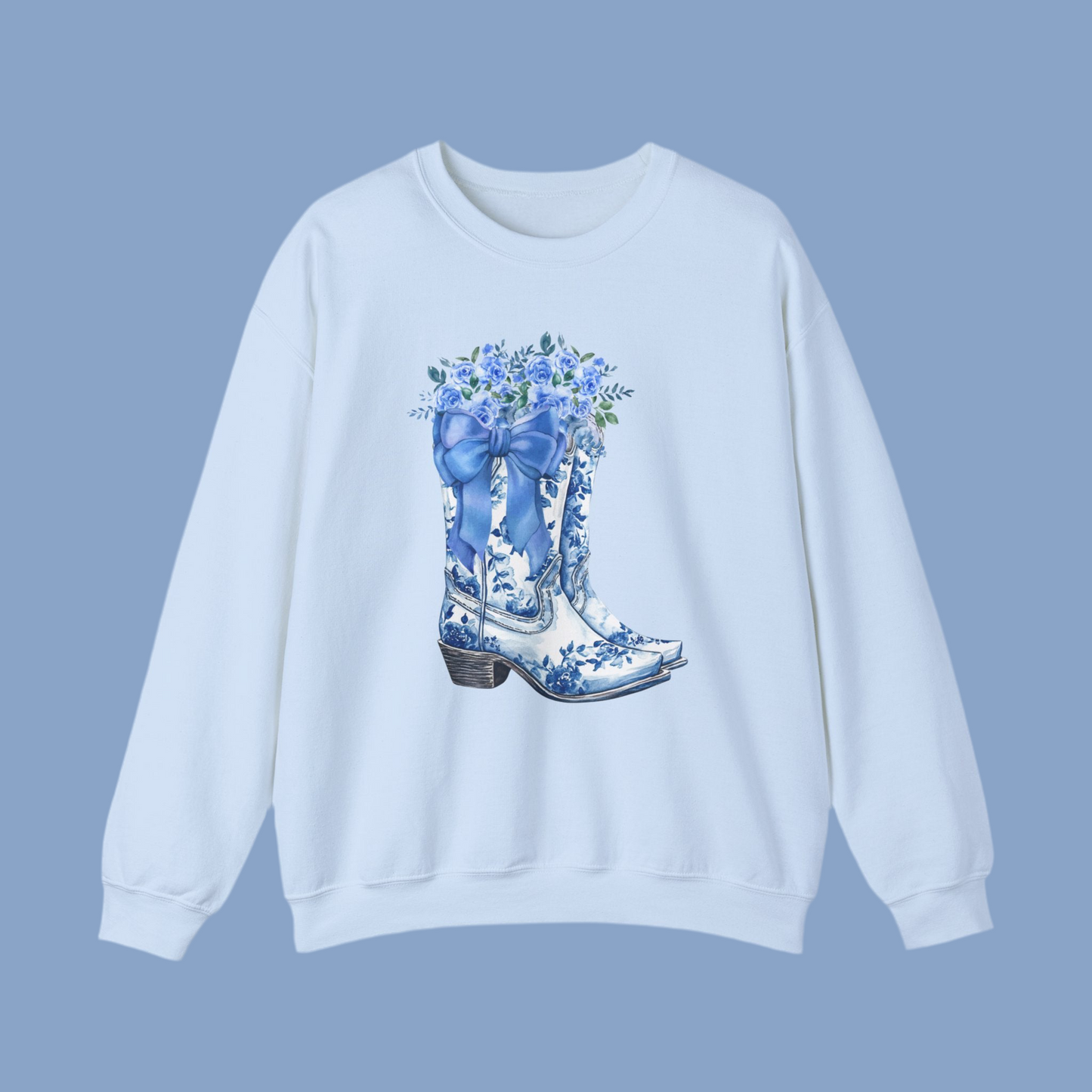 Image: This women's sweatshirt features an artistic blue toile design of cowboy boots, a charming bow, and delicate wildflowers, evoking a soft yet rustic country aesthetic. The perfect blend of cozy and stylish, it is ideal for rodeo weekends, casual outings, or layering on cool evenings. A great gift for cowgirls, western fashion lovers, or trendy moms who appreciate timeless country-inspired clothing with a feminine touch, by jaecrece.
