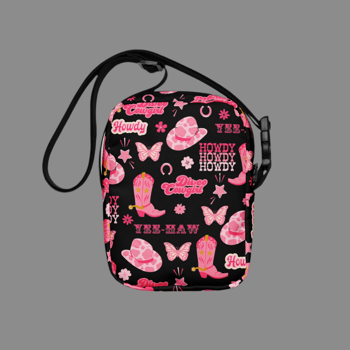 Image: Disco Cowgirl Canvas Crossbody Bag. This small black sling bag features a western glam hot pink pattern of cowgirl boots, cowgirl hats, butterflies and horseshoes. The pattern reads Disco Cowgirl, Yee-Haw and Howdy. The perfect mini backpack for bachelorette parties, gifts for teens or tweens, or trips to the state fair, by jaecrece