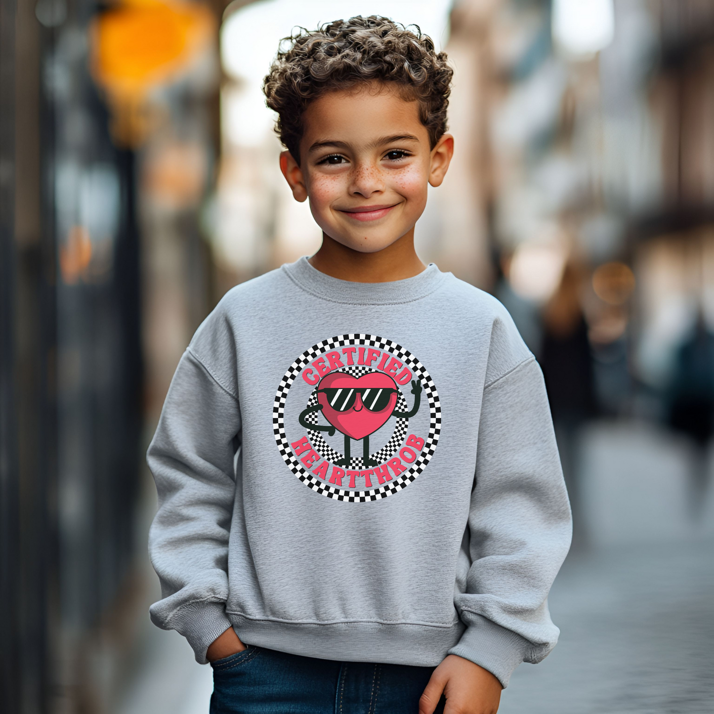 Image: Certified Heartthrob Sweatshirt. This Valentines Day sweater for boys or girls is available in white or gray. It features a checker pattern ring, with a cartoon heart man wearing sunglasses, with the text Certified Heartthrob, by jaecrece