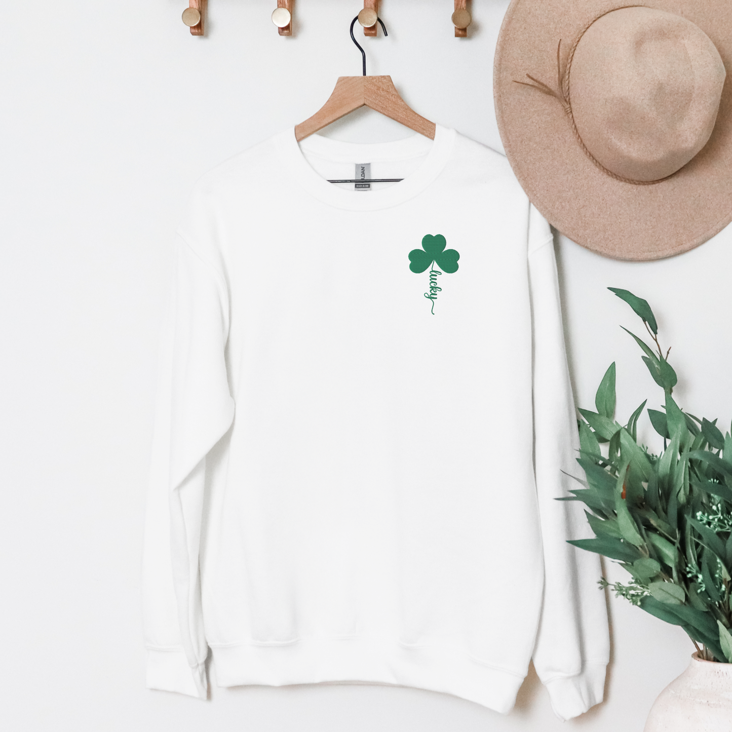 Image: St Patricks Day Emboidered Shamrock Lucky Women's Sweatshirt. This white crewneck pullover has embroidered green four leaf clover, and stem of the clover spells Lucky. This St. Pattys Day pullover sweater is also available in childrens sizes, for family matching opportunities, by jaecrece