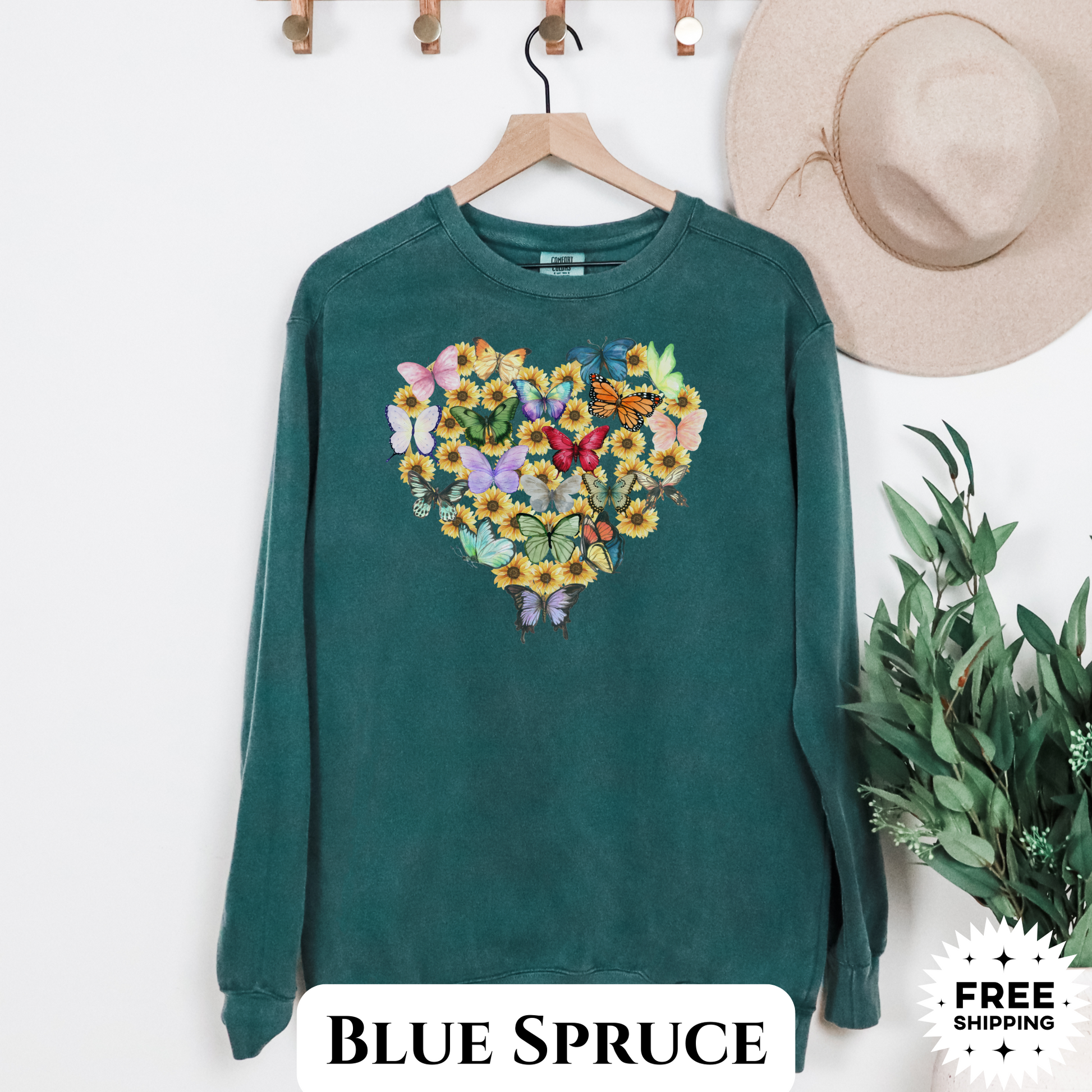 Image: Butterfly Sunflower Heart Womens Sweatshirt. This nature inspired cozy pullover sweatshirt has  watercolor wildflowers and butterflies. Comfort colors available in violet, Blue spruce and denim. Great for Earth Day, Valentines Day, by jaecrece