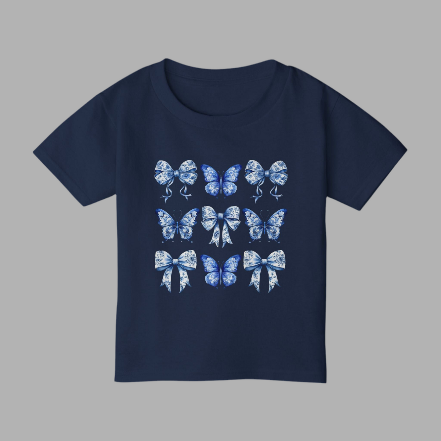 Adorable toddler girl T-shirt in soft cotton showcases a vintage blue toile design with butterflies and bows, channeling the popular Texas coquette and coastal cowgirl aesthetics. This stylish toddler tee is a wardrobe essential for spring outings, western-themed parties, and sibling matching looks. Available in sizes 2T to 6T, it makes an excellent gift for southern sweethearts or beachy boho babies, by jaecrece.