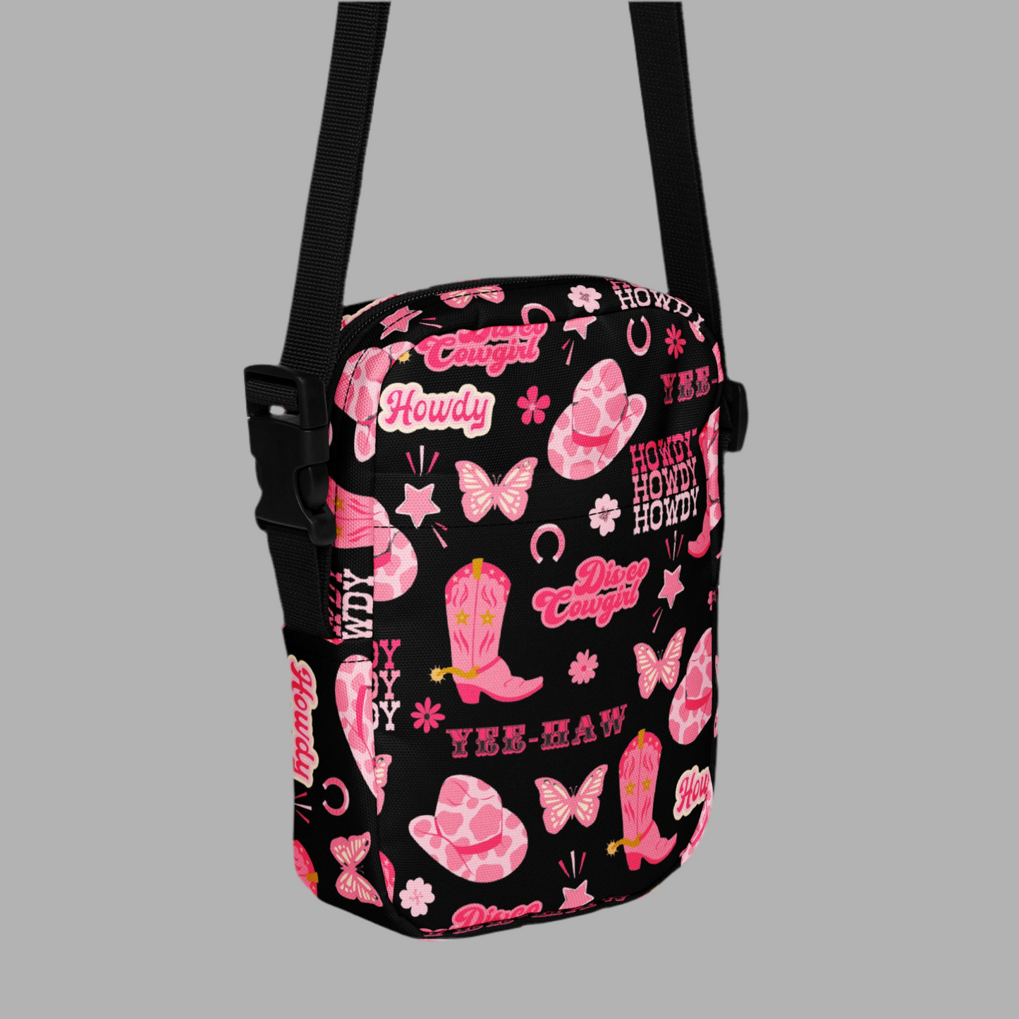 Image: Disco Cowgirl Canvas Crossbody Bag. This small black sling bag features a western glam hot pink pattern of cowgirl boots, cowgirl hats, butterflies and horseshoes. The pattern reads Disco Cowgirl, Yee-Haw and Howdy. The perfect mini backpack for bachelorette parties, gifts for teens or tweens, or trips to the state fair, by jaecrece