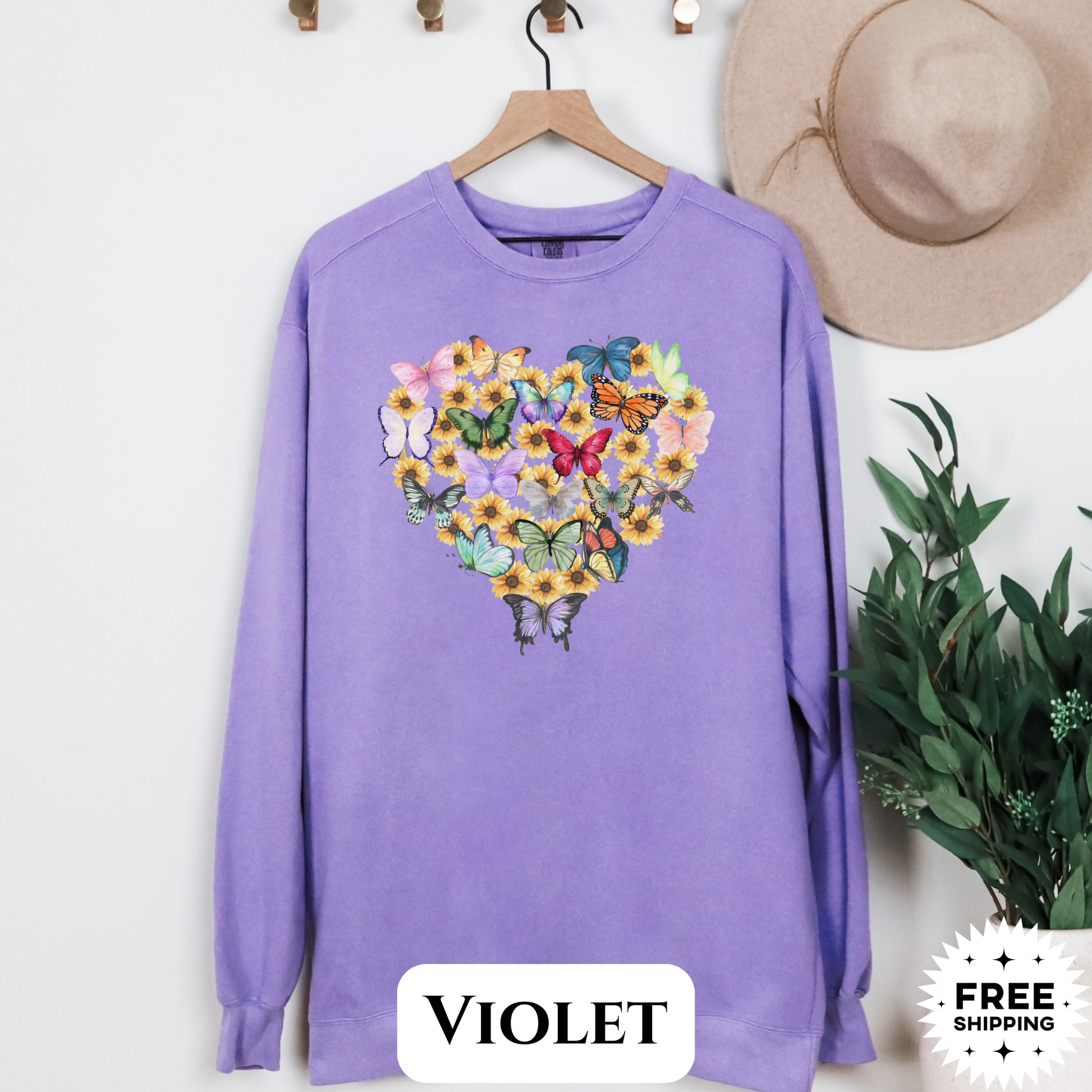 Image: Butterfly Sunflower Heart Womens Sweatshirt. This nature inspired cozy pullover sweatshirt has  watercolor wildflowers and butterflies. Comfort colors available in violet, Blue spruce and denim. Great for Earth Day, Valentines Day, by jaecrece