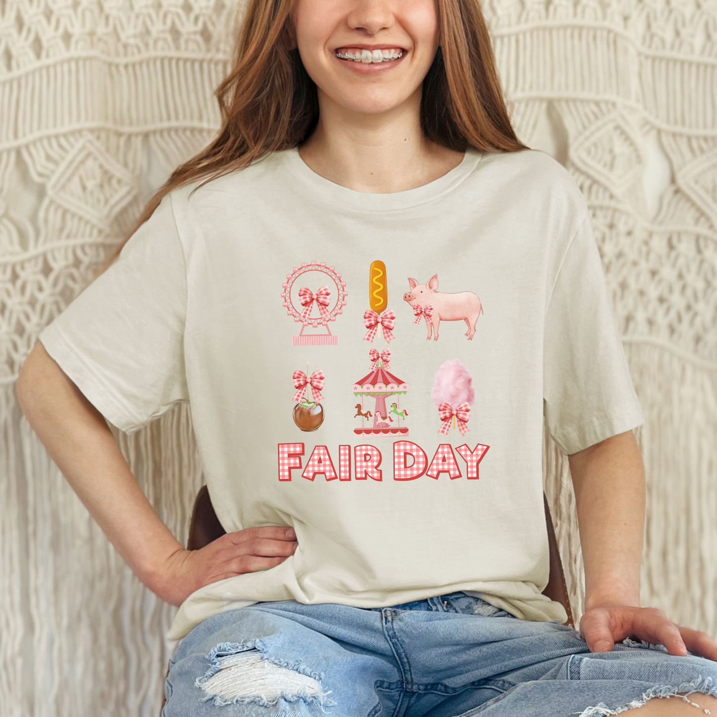 Image: A playful Fair Day graphic tee with red and white gingham lettering, designed for fair lovers of all ages. Featuring a collage of fair inspired images including a pig, Ferris wheel, caramel apple, and corndog, this shirt brings the fun of the fair to life. Designed with a soft girl coquette look, it is perfect for family matching outfits at the state fair, livestock shows, or carnival themed birthday parties, available in toddler, girl, and women’s sizes, by jaecrece.