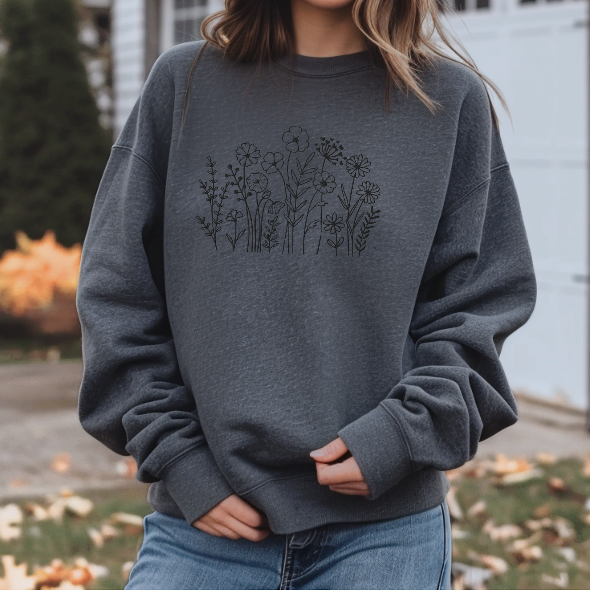 Image: A cozy dark grey sweatshirt with delicate black wildflower embroidery across the chest, showcasing a minimalist yet elegant botanical design. The soft fabric drapes effortlessly, offering comfort for everyday wear. This floral nature crewneck is perfect for layering, adding a subtle floral charm to casual outfits. A thoughtful gift for plant lovers or those who appreciate nature-inspired fashion, by jaecrece.