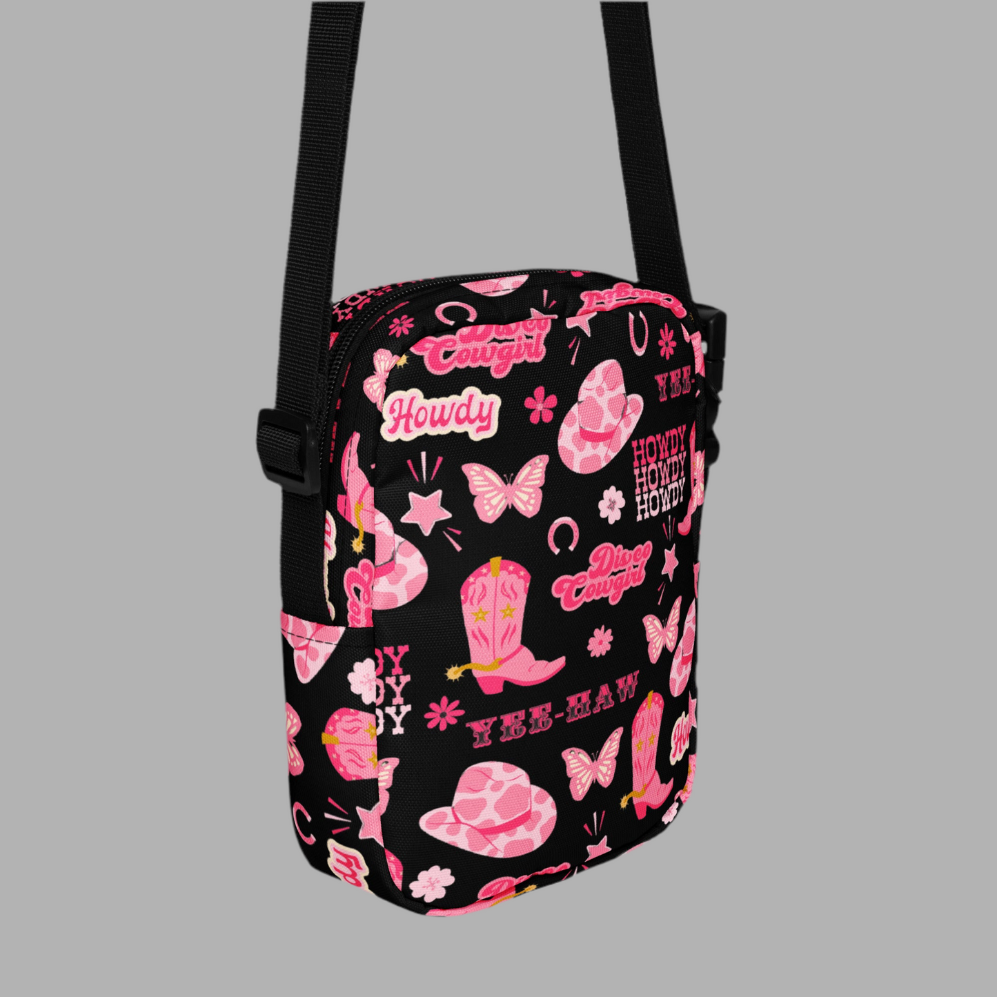 Image: Disco Cowgirl Canvas Crossbody Bag. This small black sling bag features a western glam hot pink pattern of cowgirl boots, cowgirl hats, butterflies and horseshoes. The pattern reads Disco Cowgirl, Yee-Haw and Howdy. The perfect mini backpack for bachelorette parties, gifts for teens or tweens, or trips to the state fair, by jaecrece