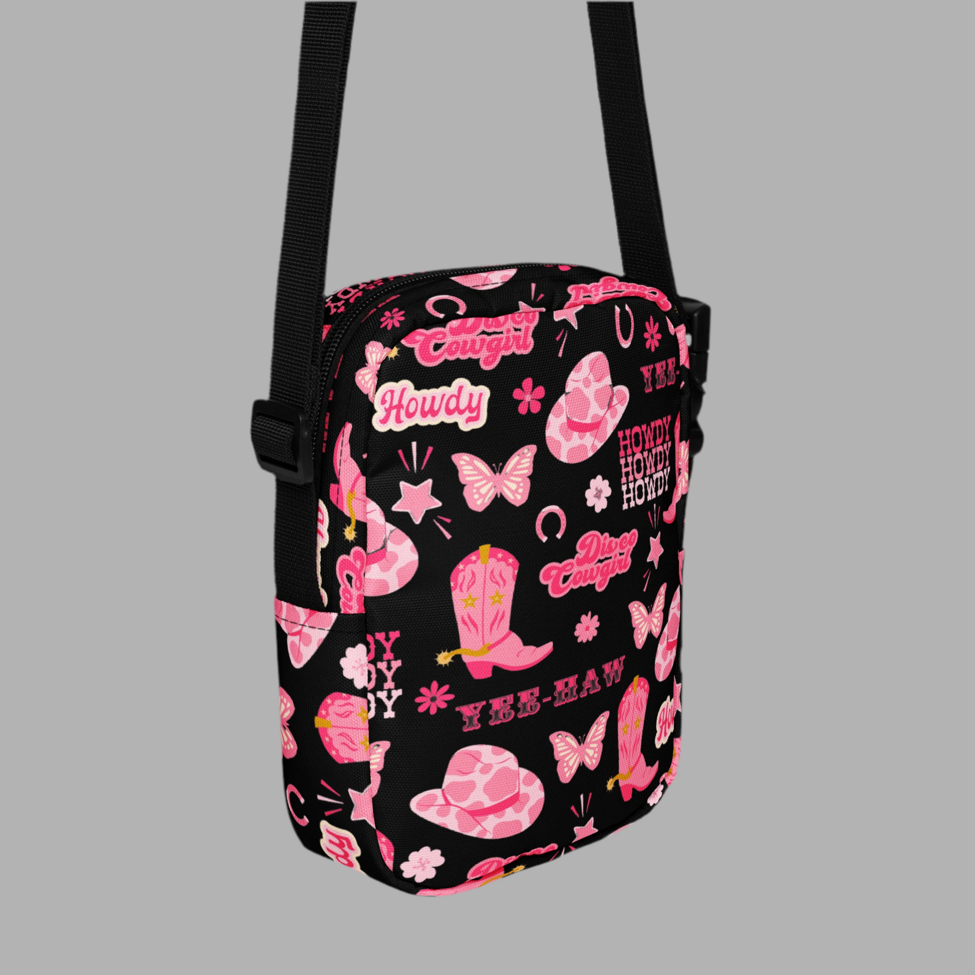 Image: Disco Cowgirl Canvas Crossbody Bag. This small black sling bag features a western glam hot pink pattern of cowgirl boots, cowgirl hats, butterflies and horseshoes. The pattern reads Disco Cowgirl, Yee-Haw and Howdy. The perfect mini backpack for bachelorette parties, gifts for teens or tweens, or trips to the state fair, by jaecrece