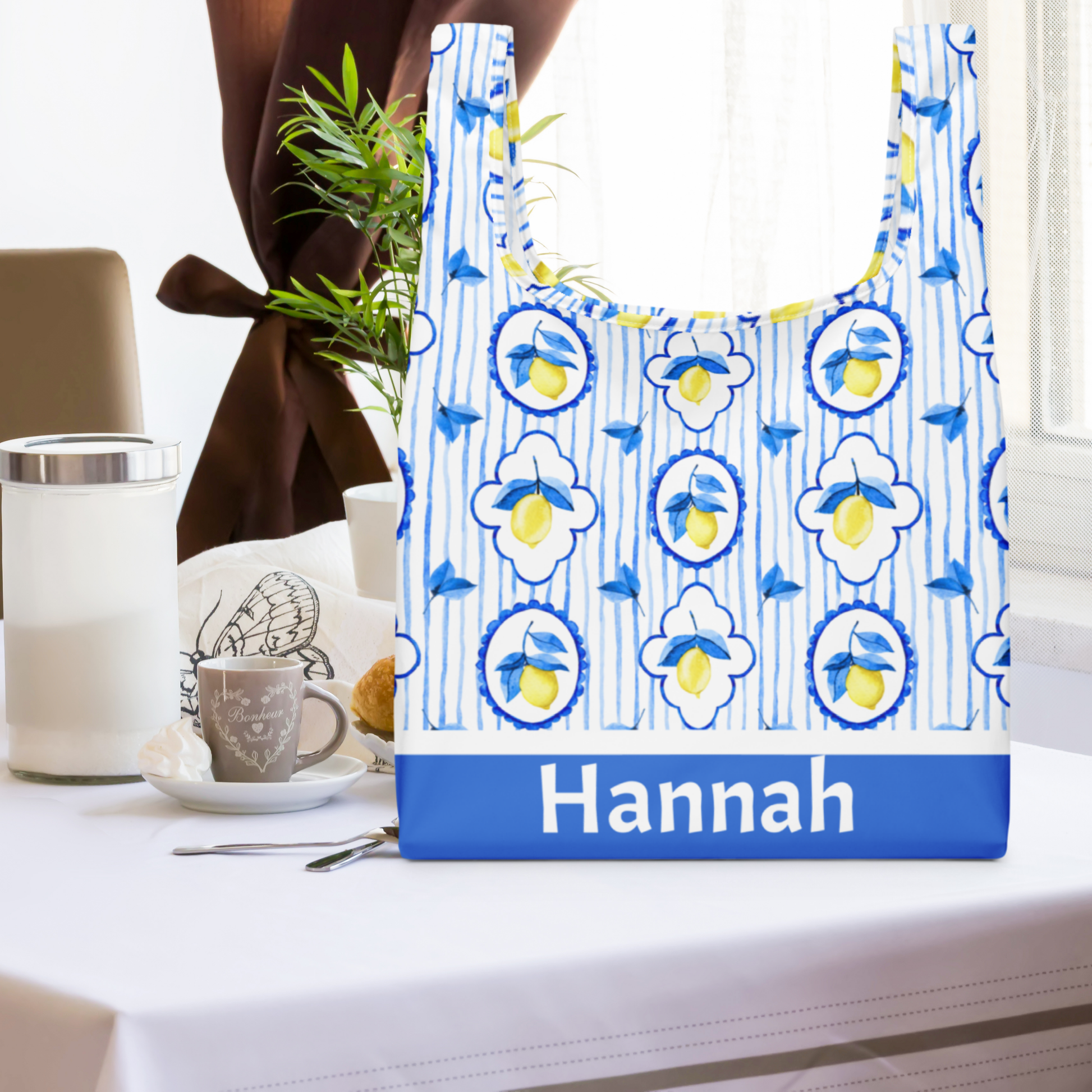 Amalfi Lemon Tote Bag featuring a vibrant Italian summer design with lemons and blue Mediterranean tile print, perfect for eco conscious shopping, travel, and beach days. Made from durable polyester with straps built into the bag for strength that won’t rip. Bag measures 15.5" × 25.3" unfolded and folds neatly with an elastic band for storage. Great personalized gift for her, farmers market trips, or Italy inspired travel.