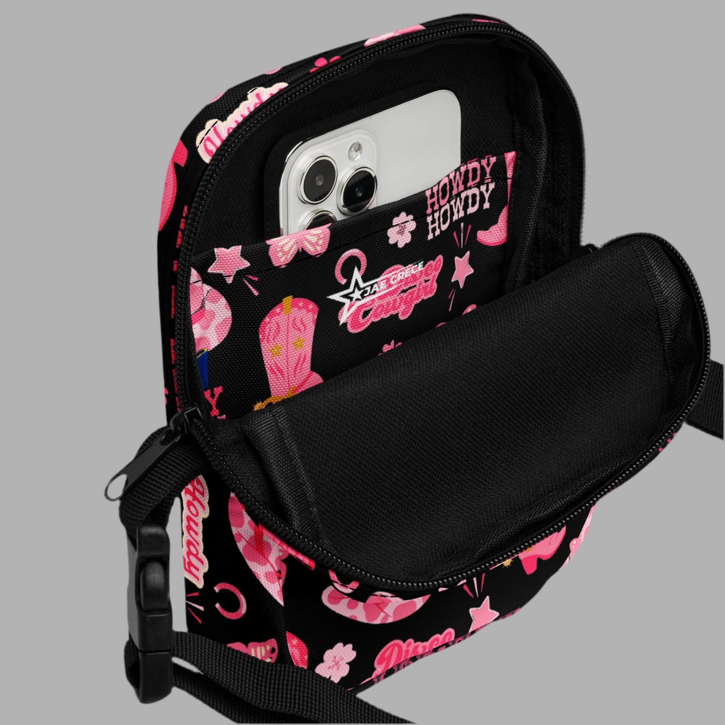Image: Disco Cowgirl Canvas Crossbody Bag. This small black sling bag features a western glam hot pink pattern of cowgirl boots, cowgirl hats, butterflies and horseshoes. The pattern reads Disco Cowgirl, Yee-Haw and Howdy. The perfect mini backpack for bachelorette parties, gifts for teens or tweens, or trips to the state fair, by jaecrece