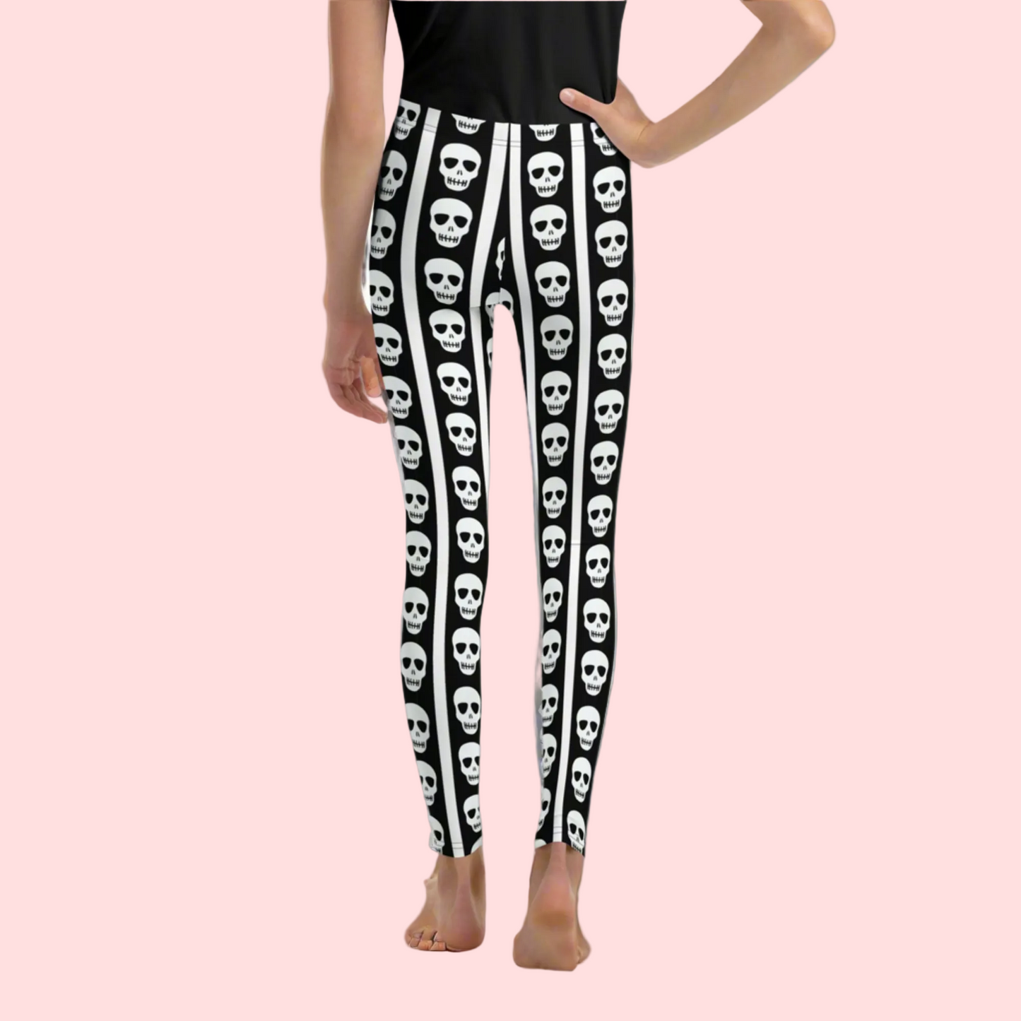 Black and white skull youth leggings featuring repeating skull pattern between vertical stripes. Trendy leggings for girls and tweens sizes 8 to 20 designed for comfort and all day wear. Perfect Halloween outfit for tweens, school fall fashion, or casual spooky aesthetic style. Soft stretchy fabric ideal for active kids who love gothic inspired clothing and fun seasonal statement outfits.