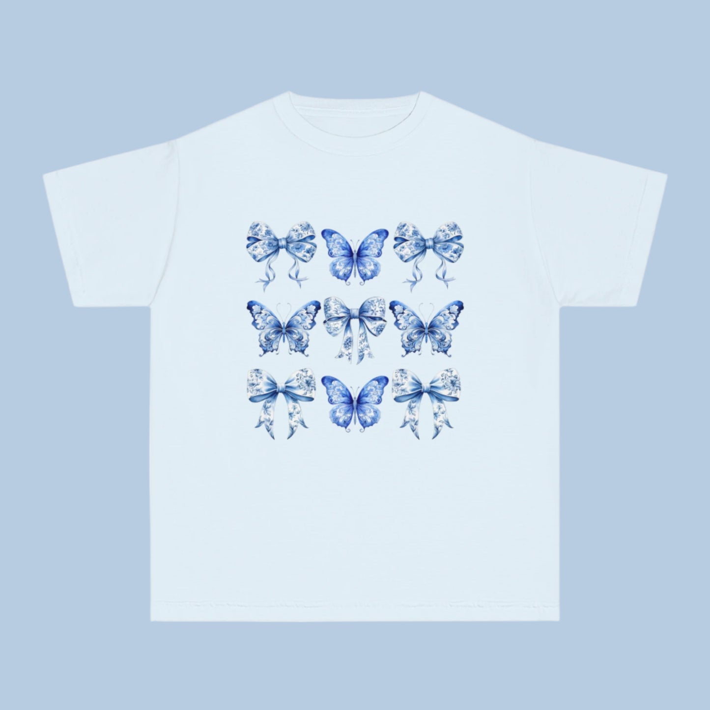 Image: Classic girls’ Comfort Colors T-shirt with a dreamy Blue Toile Butterflies & Bows print, perfect for teens and tweens who love vintage charm, butterfly fashion, or trending coquette aesthetic. Sizes XS–XL available in Chambray, White, True Navy, and Pepper. A soft girl staple and perfect for southern events or casual wear. Coordinates with women’s and toddler leggings or tees for mommy and me outfits, by jaecrece.