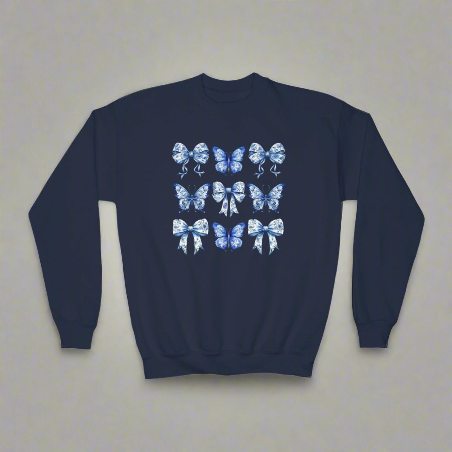 Blue Toile Girls Sweatshirt with delicate bow and butterfly details in a classic navy and white toile pattern. Sizes XS–XL fit girls and tweens comfortably. Soft and cozy, perfect for spring or fall layering, casual outfits, or family events. Embraces soft girl aesthetic, Texas coquette, coastal cowgirl, and whimsical cottagecore trends. Part of a matching family collection, ideal for sibling coordination or mom and daughter photo outfits. Makes a thoughtful birthday gift or stylish wardrobe staple for girl