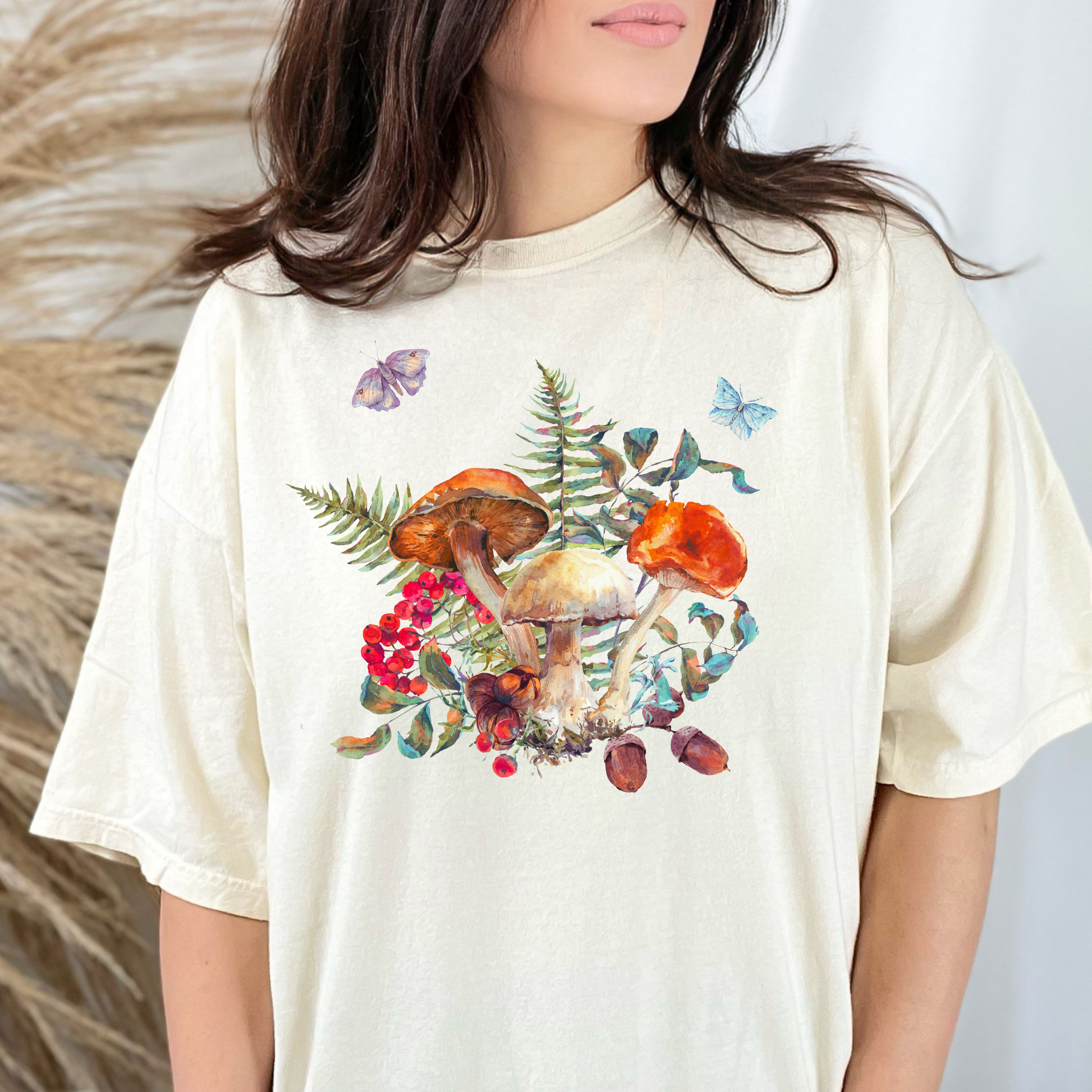 Boho Botanical Mushroom Shirt printed on a Comfort Colors 1717 tee, featuring whimsical garden-inspired mushrooms, ferns, butterflies, moths, berries, and acorns. This unisex woodland shirt in earthy tones like Ivory, Blue Spruce, Butter, Granite, and Pepper is perfect for goblincore, gardencore, fairyboho, and boho mystic enthusiasts. Ideal for fall, autumn, casual layering, cottagecore outfits, and plant lover fashion, this made-to-order boho tee makes a thoughtful gift for nature lovers, mushroom enthusi