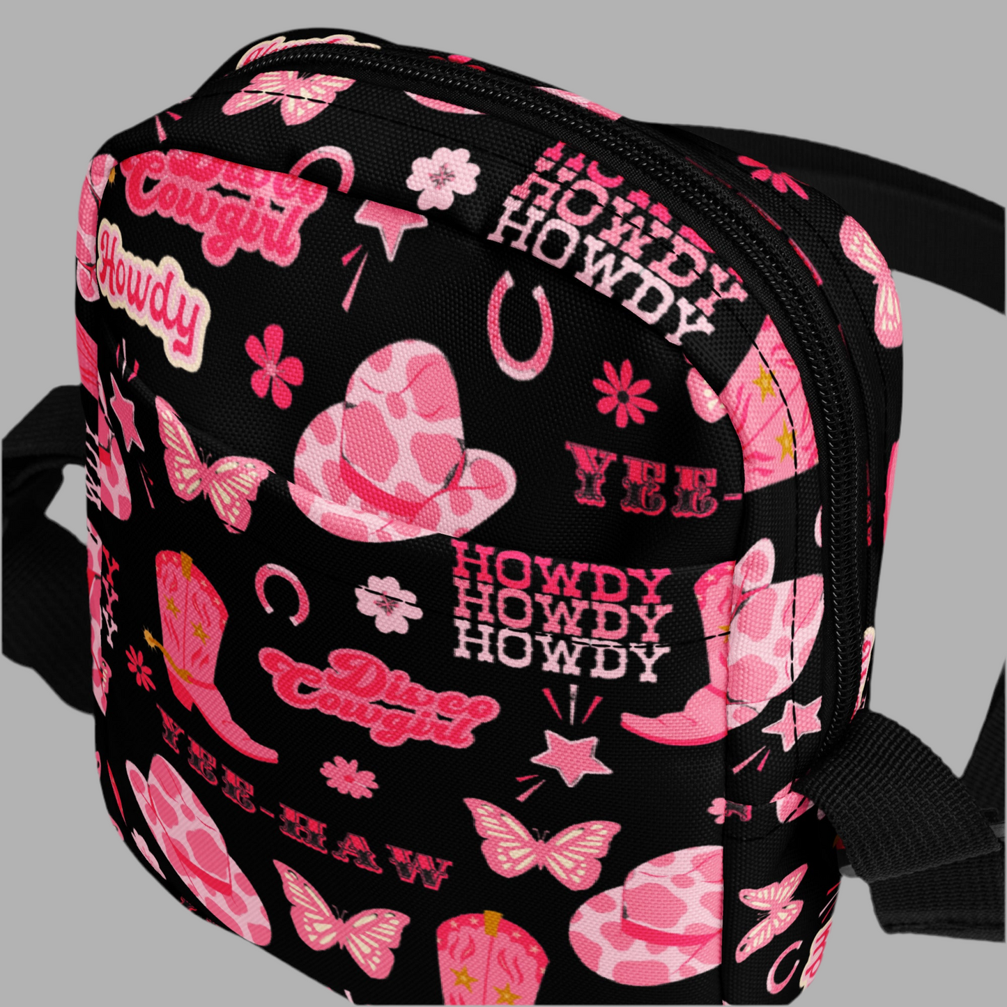 Image: Disco Cowgirl Canvas Crossbody Bag. This small black sling bag features a western glam hot pink pattern of cowgirl boots, cowgirl hats, butterflies and horseshoes. The pattern reads Disco Cowgirl, Yee-Haw and Howdy. The perfect mini backpack for bachelorette parties, gifts for teens or tweens, or trips to the state fair, by jaecrece