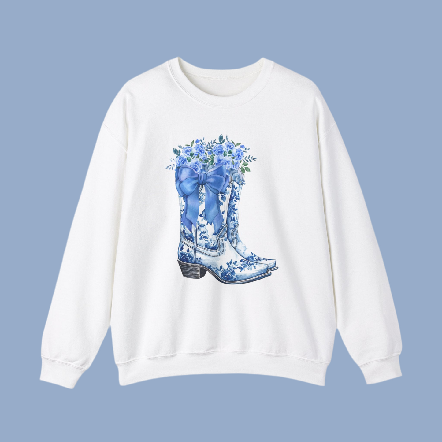 Image: With a soft toile print of cowboy boots, a blue bow, and wildflowers, this sweatshirt brings country elegance to a cozy pullover. The feminine western design is perfect for pairing with jeans and boots for a classic cowgirl look. Whether you are shopping for a daughter who loves country concerts or a mama who enjoys western fashion, this sweatshirt is a perfect wardrobe addition that offers comfort and style in equal measure, by jaecrece.