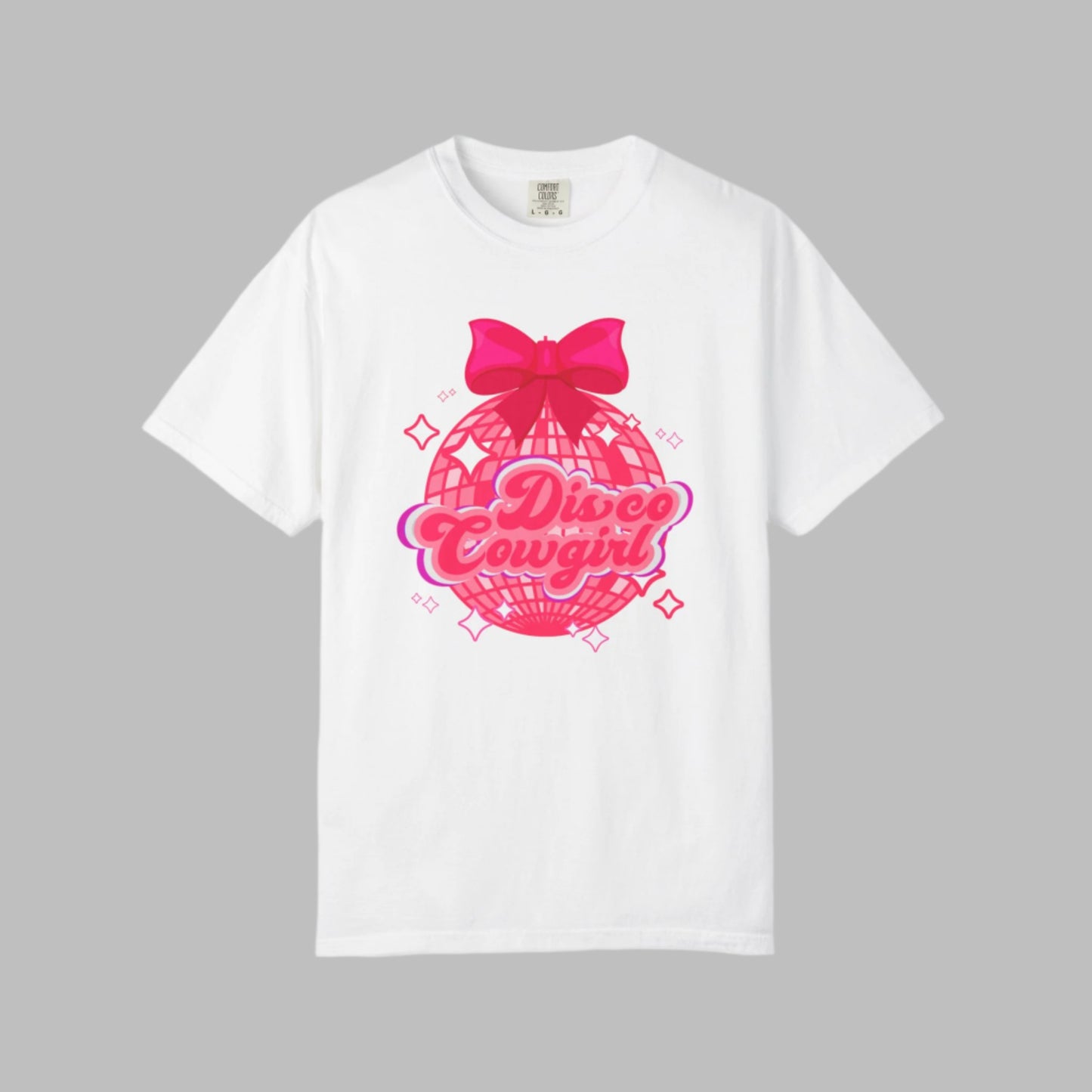 Comfort Colors Disco Cowgirl tee for women featuring bold pink script, sparkly disco ball, and hot pink bow for a festive coquette vibe. Great for rodeo season, girls' trips, and honky tonk nights. A retro-inspired western shirt made for comfort and fun in black, pepper, ivory, and white, S–4XL. Matching sweatshirt available for the full look.