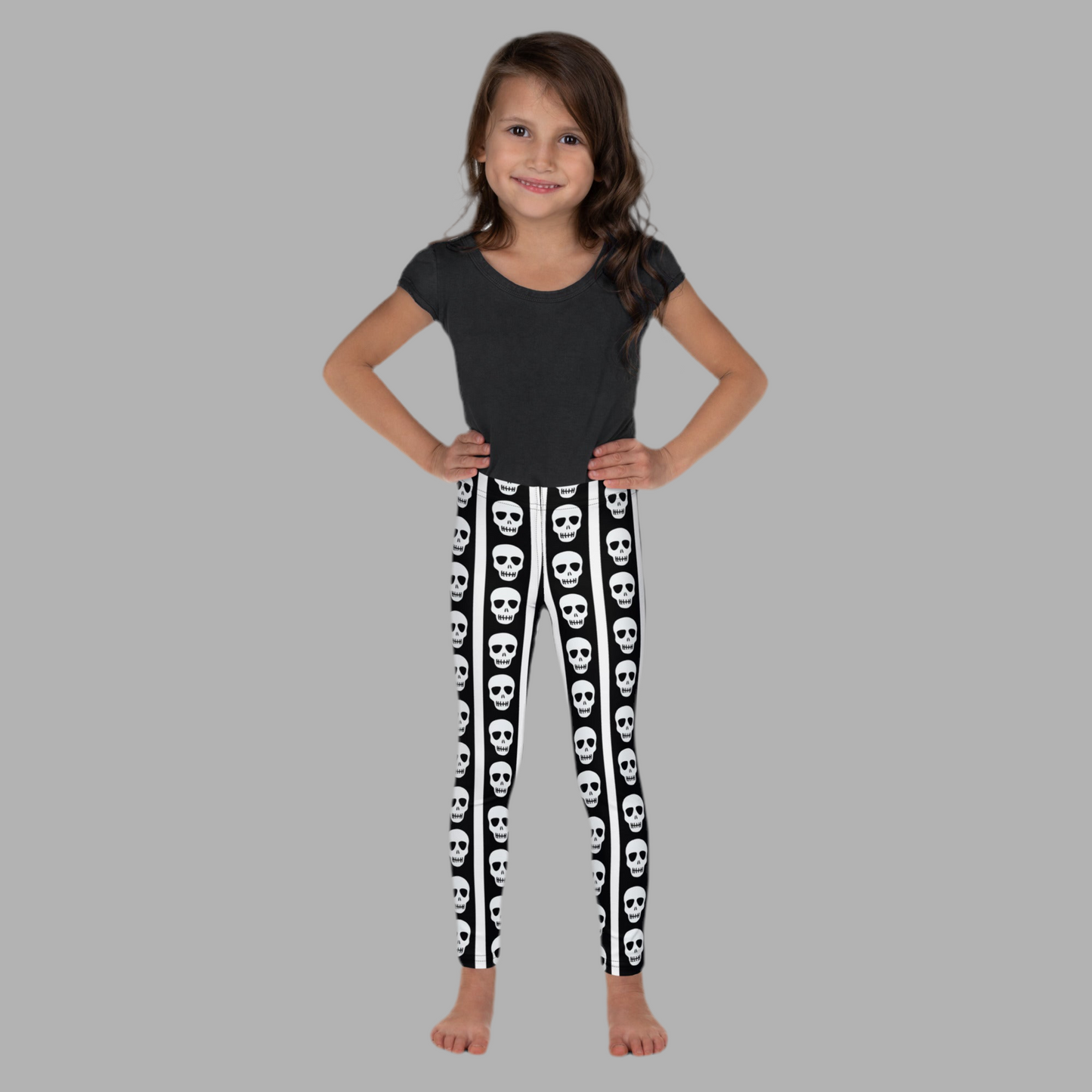 Image: A fun mix of cute and creepy, these kids leggings are decorated with black and white stripes and feature skull graphics marching down both legs. Great for little ghouls who love bold fashion, these comfy leggings are ideal for parties, pretend play, or everyday adventures. Available in toddler and youth sizes, they add spooky flair to any mini wardrobe, by jaecrece.