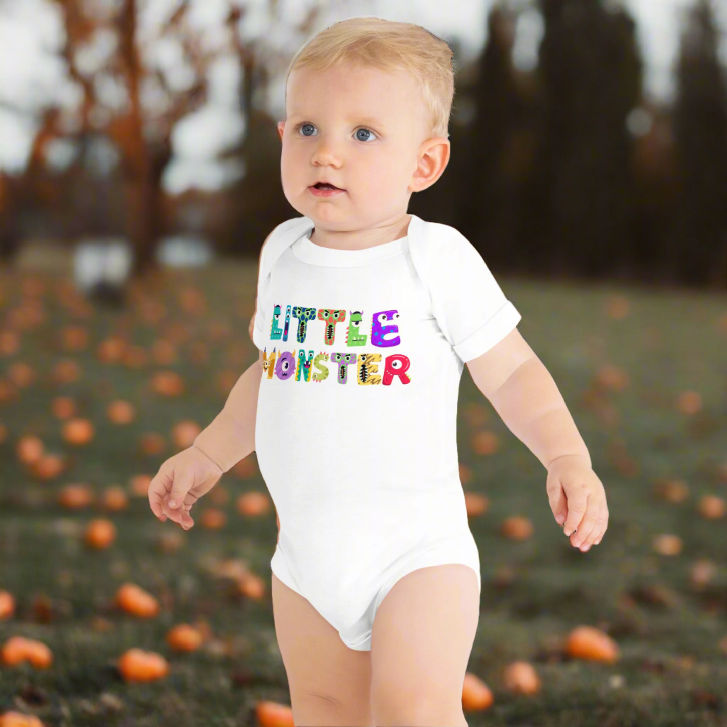 Baby boy outdoors at a fall Halloween event wearing the Little Monster bodysuit, with playful cartoon monster letters spelling “little monster” on the front. This festive baby one-piece, printed on a soft Bella + Canvas 100B, makes an adorable first Halloween outfit or cozy fall romper. Designed with an envelope neckline and snap closure for easy changing, this cotton baby bodysuit is available in black or white, newborn through 24 months, and makes a thoughtful baby shower gift.