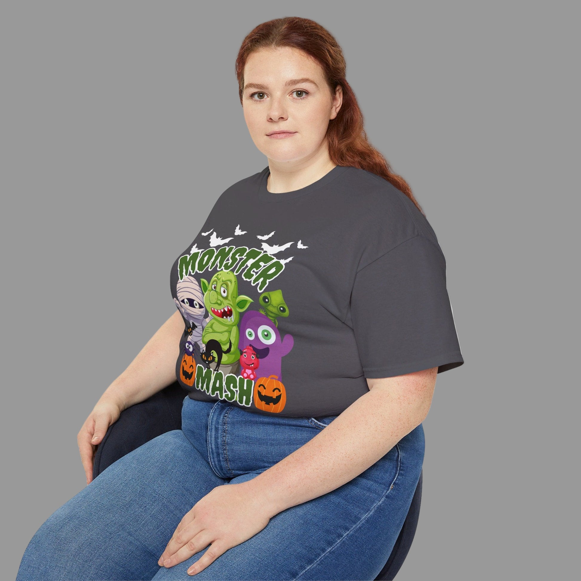 Adult Halloween graphic t-shirt featuring a Monster Mash cartoon design with playful spooky characters including a mummy, pumpkins, troll, bats, and spider. Printed on the Gildan 2000, this shirt is made of breathable 100% cotton, available in black or charcoal, and offered in sizes S–5XL. Great for creating matching Halloween outfits, casual spooky season style, or gifting to friends and family who love Halloween and fall celebrations.