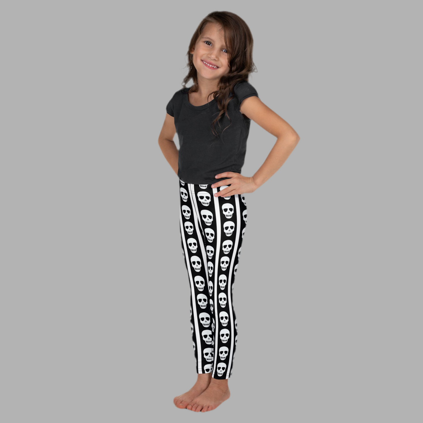 Image: A fun mix of cute and creepy, these kids leggings are decorated with black and white stripes and feature skull graphics marching down both legs. Great for little ghouls who love bold fashion, these comfy leggings are ideal for parties, pretend play, or everyday adventures. Available in toddler and youth sizes, they add spooky flair to any mini wardrobe, by jaecrece.