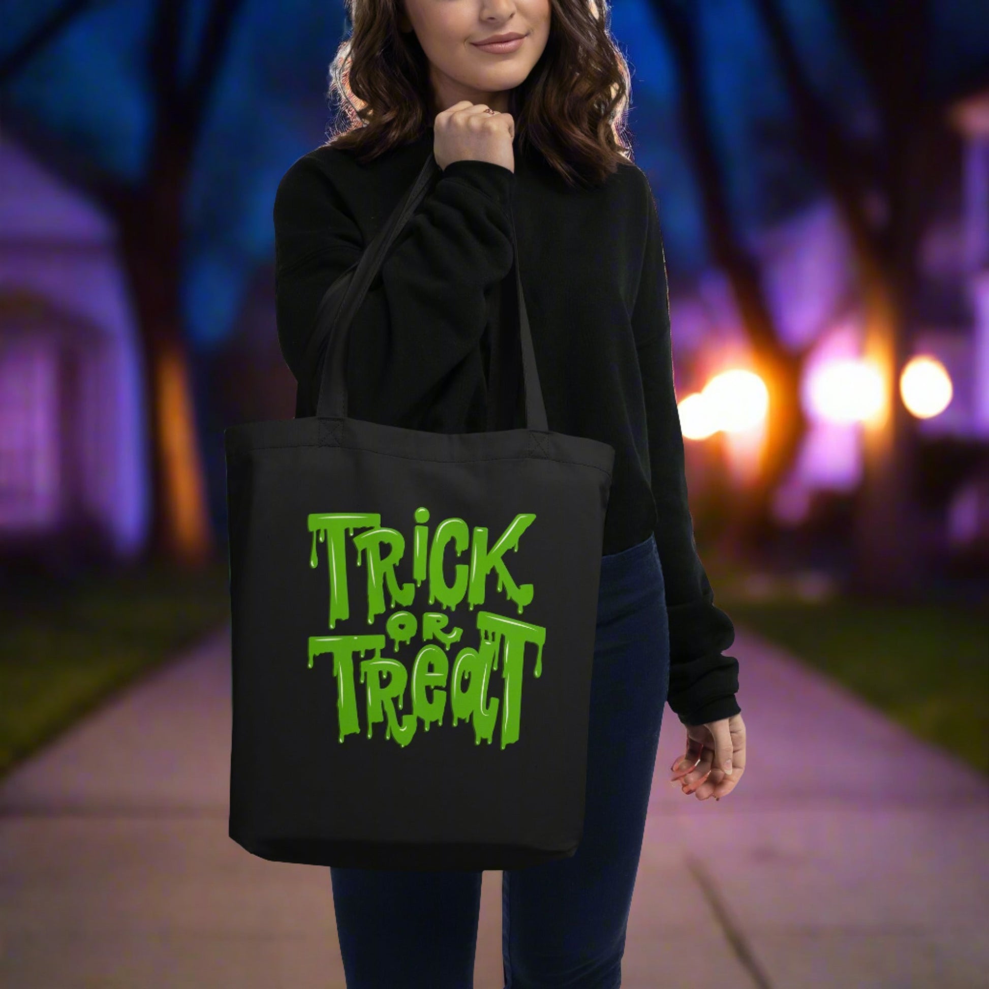 Eco-friendly Trick or Treat Tote Bag in black with bright green slime lettering, made from 100% organic cotton. This reusable Halloween candy bag is durable, spacious, and perfect for trick-or-treating, pumpkin patch visits, or everyday use. Holds up to 30 lbs, making it ideal for large candy hauls or carrying books, groceries, or essentials. A sustainable alternative to plastic Halloween buckets with a spooky and fun design.