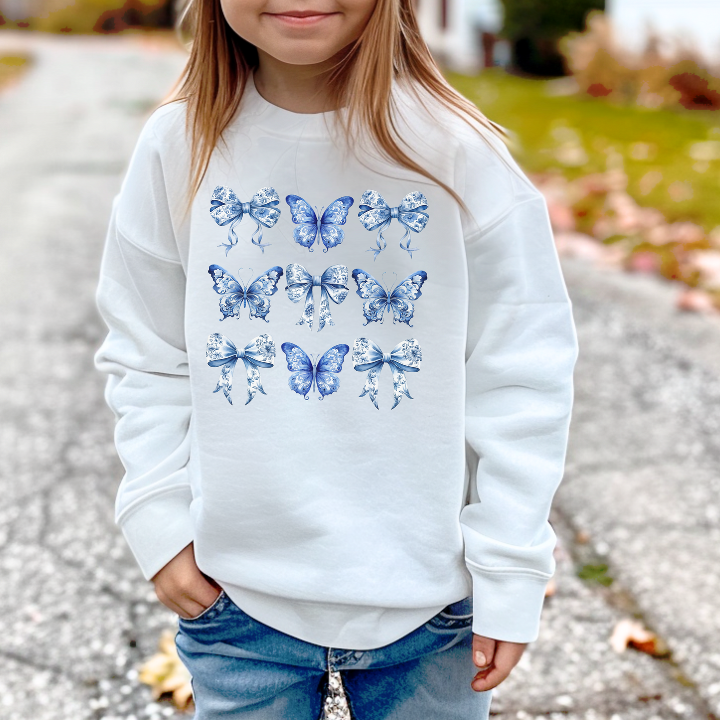 Image: Classic blue toile sweatshirt for girls features delicate butterfly and bow details. Coastal cowgirl meets Southern belle in this charming pullover, available in youth sizes XS to XL. The soft material and relaxed fit are ideal for stylish comfort. Great for layered looks, matching sibling outfits, or coordinated family events. A fresh pick for girls who love cute fashion with a vintage flair, by jaecrece.