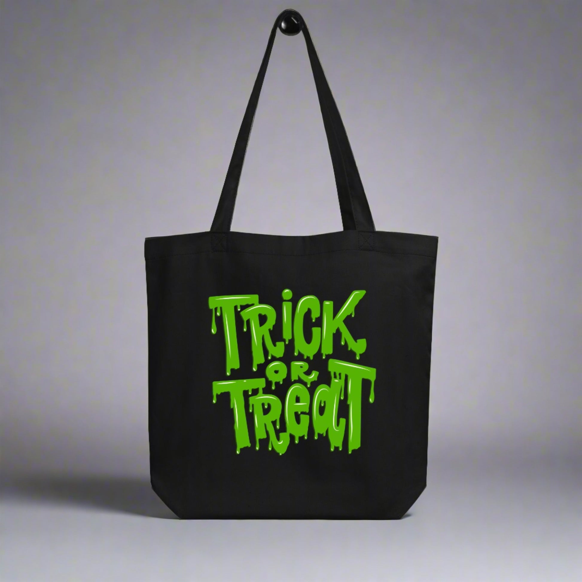 Reusable Trick or Treat Tote Bag with green ooze lettering, printed on black organic cotton. Designed for eco-friendly trick-or-treating, this Halloween candy bag is durable, holds up to 30 lbs, and makes a sustainable alternative to disposable bags. Perfect for kids and adults, this versatile tote doubles as a spooky everyday bag, Halloween party favor, or gift for families who want practical style during spooky season.