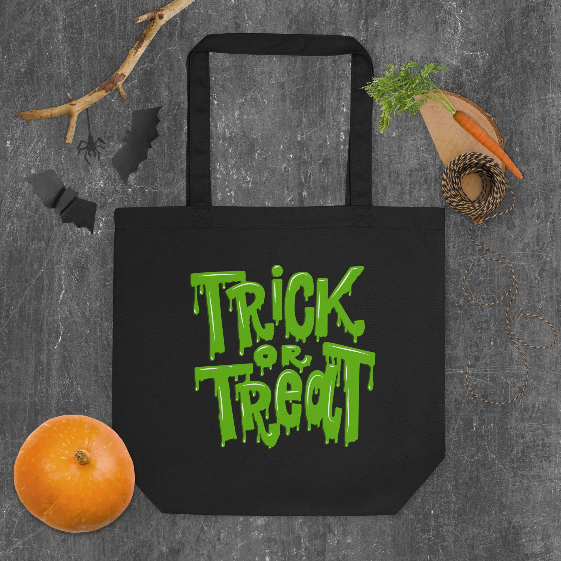 Black Trick or Treat Tote Bag with green slime font, crafted from 100% organic cotton for eco-friendly Halloween fun. Perfect as a trick-or-treat candy bag for kids or adults, this reusable tote holds up to 30 lbs and is built to last beyond Halloween night. Ideal for carrying candy, party favors, or everyday essentials, this sustainable Halloween bag combines spooky style with durability and practical function.