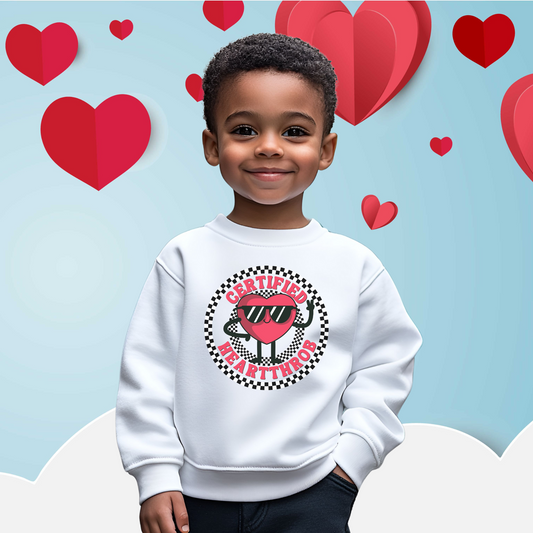 Image: Certified Heartthrob Sweatshirt. This Valentines Day sweater for boys or girls is available in white or gray. It features a checker pattern ring, with a cartoon heart man wearing sunglasses, with the text Certified Heartthrob, by jaecrece