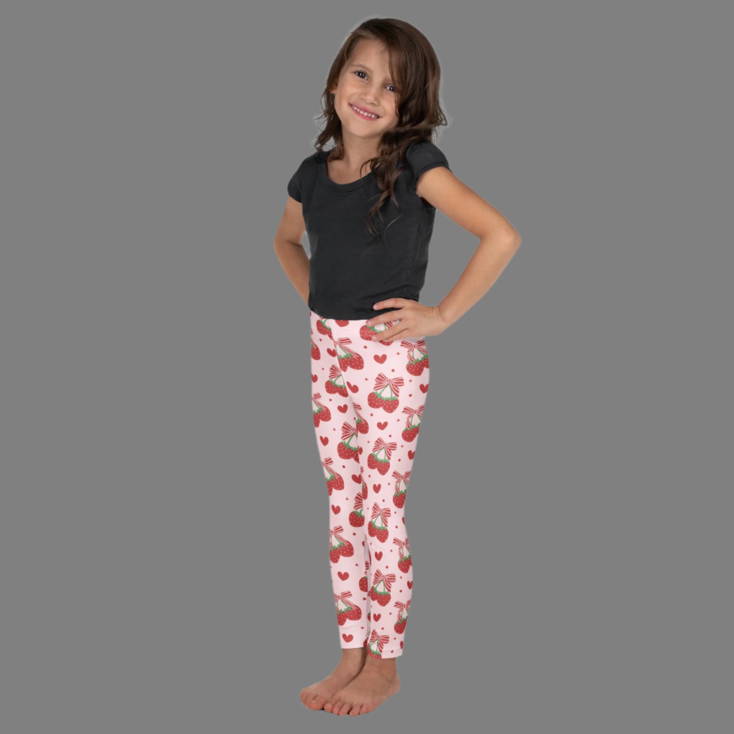 Image: These pastel pink leggings for girls and toddlers feature a whimsical strawberry and red bow pattern. Made in sizes 2T through 7, they’re ideal for playful kids who love bright colors and fun prints. Whether worn with sneakers or sandals, these leggings are a charming pick for school, playtime, or family outings. A thoughtful and cute gift for little trendsetters, by jaecrece.
