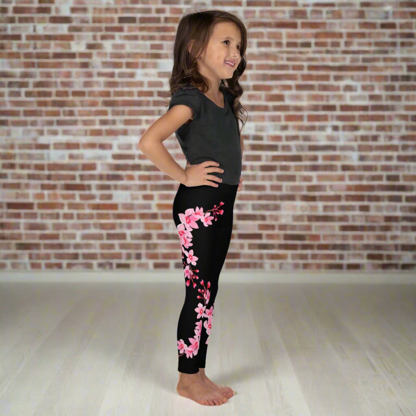 Image: Japanese Cherry Blossom Girls and Toddler Leggings, in sizes 2T, 3t, 4T, 5T, 6, 6X and 7. Black leggings with a swirl of Japanese cherry blossoms going down the outside of each leg. Elastic, soft, and durable with vibrant colors. Part of a matching collection for younger children and women, each pair is precision-cut and hand-sewn for a perfect fit.
