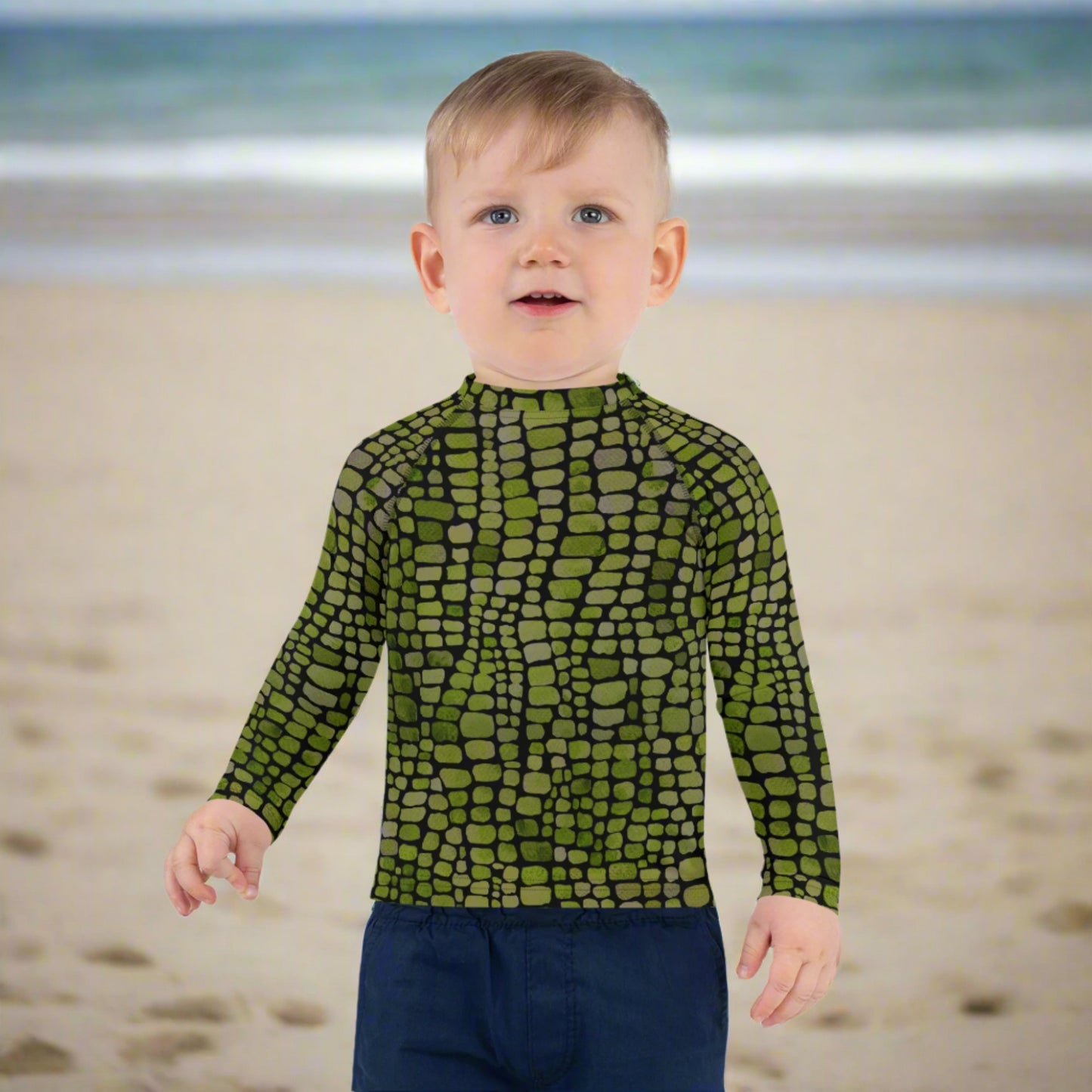 Toddler swim rash guard with green reptile pattern, perfect for water adventures or jungle-themed costumes. Available in 2T–7, this swim shirt features sun-blocking sleeves and bold scale graphics ideal for dinosaur, lizard, or snake lovers. Great for poolside dress-up or imaginative beach days. Unisex fit, soft feel, and made for active little ones.