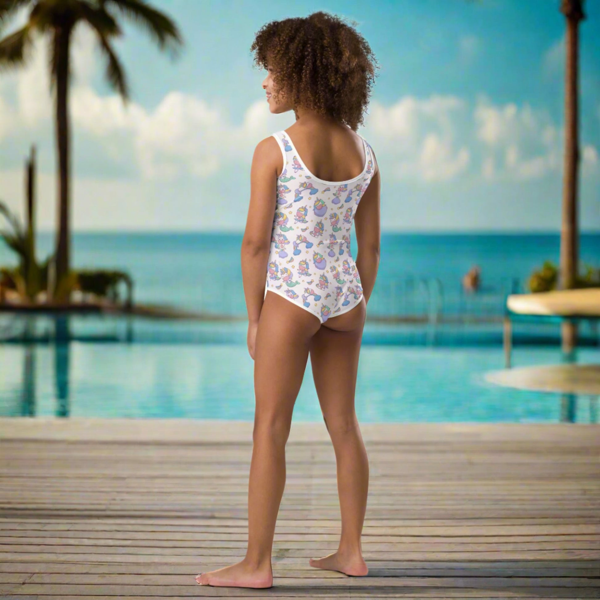 Image: Child bathing suit in toddler and girl sizes 2T-7, featuring a pink background with a cute Kawaii whimsical creature pattern of unicorn mermaids, rainbows and stars. Perfect as a Christmas gift, birthday present, or for your childs next pool party, by jaecrece