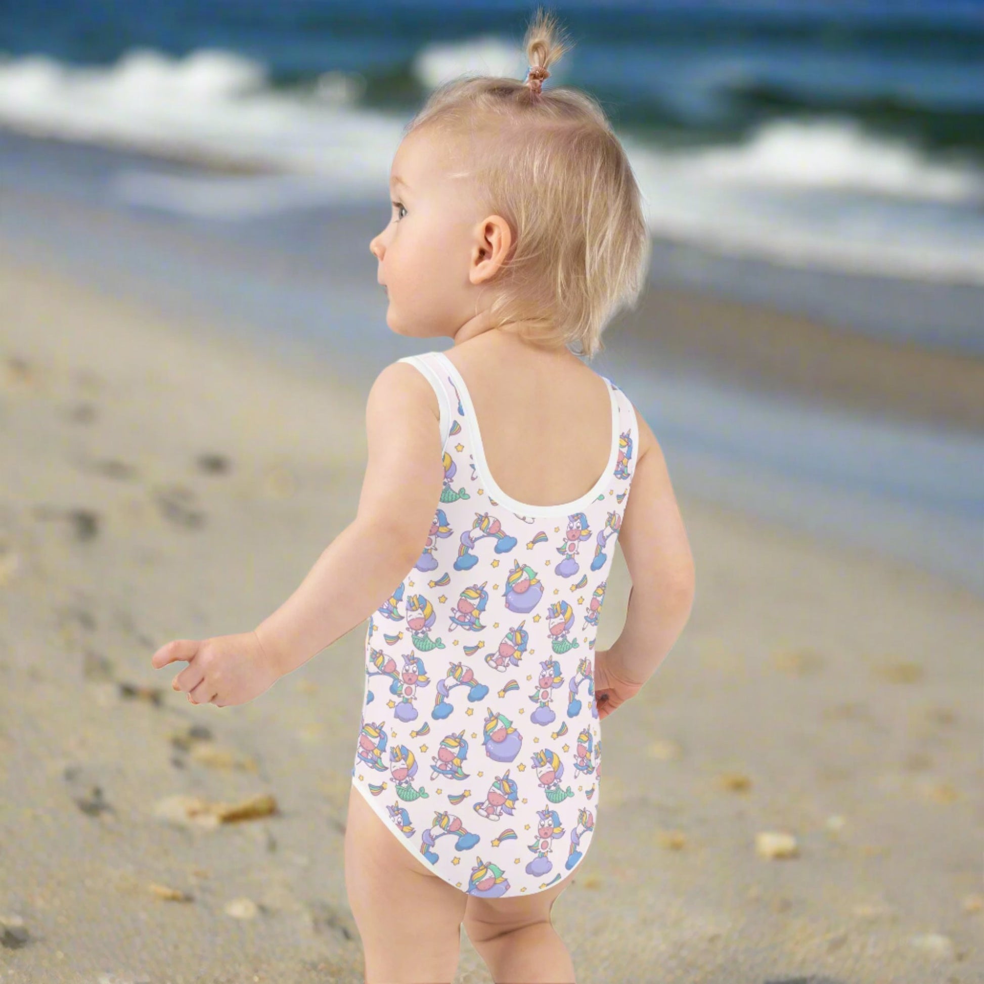Image: Child bathing suit in toddler and girl sizes 2T-7, featuring a pink background with a cute Kawaii whimsical creature pattern of unicorn mermaids, rainbows and stars. Perfect as a Christmas gift, birthday present, or for your childs next pool party, by jaecrece