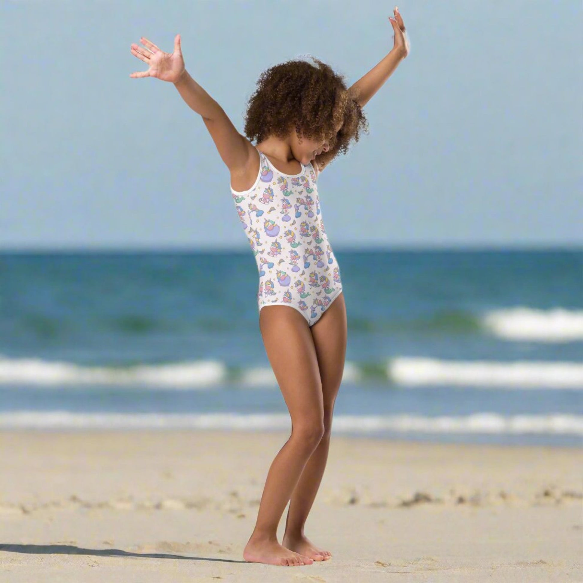 Image: Child bathing suit in toddler and girl sizes 2T-7, featuring a pink background with a cute Kawaii whimsical creature pattern of unicorn mermaids, rainbows and stars. Perfect as a Christmas gift, birthday present, or for your childs next pool party, by jaecrece