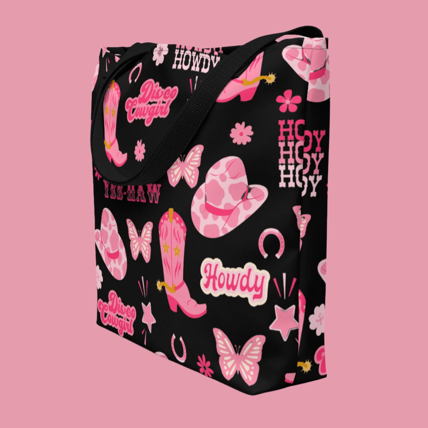 Image: Disco Cowgirl Tote Bag. This western glam canvas shoulder bag has a black background with a pink, white and pink pattern of butterflies, daisies, cowgirl hats and boots. The text on the bag reads Howdy, Yee-Haw and Disco Cowgirl. Great for weekend girls trips or bachelorette parties in Nashville, by jaecrece