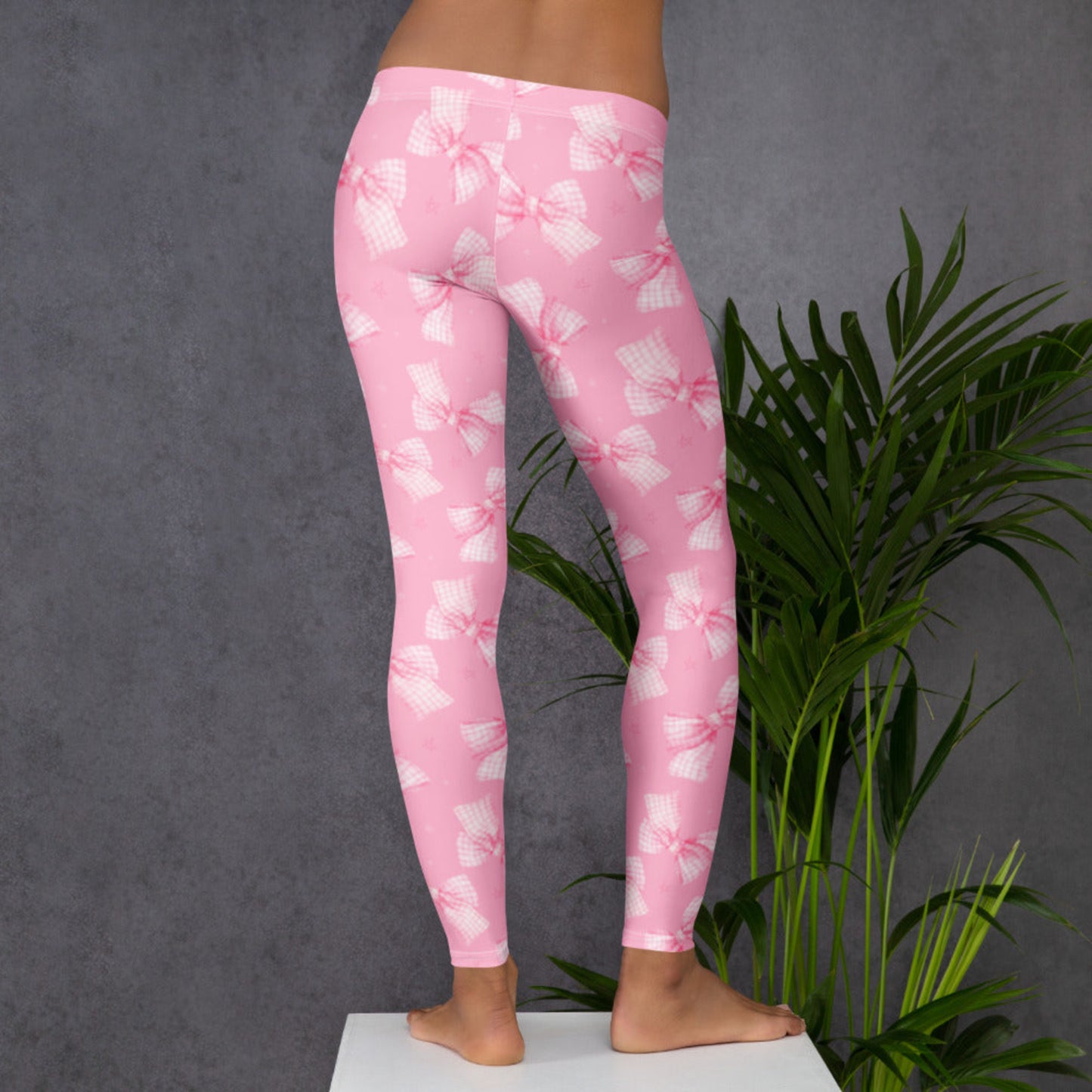 Image: Pink Bow Coquette Women’s Leggings displayed folded on a soft bed with coordinating toddler and youth sizes nearby. A must have for fans of pink fashion, bow print designs, and comfy mom and me outfits. Perfect for photo shoots, holidays, or simply relaxing at home in style, by jaecrece.