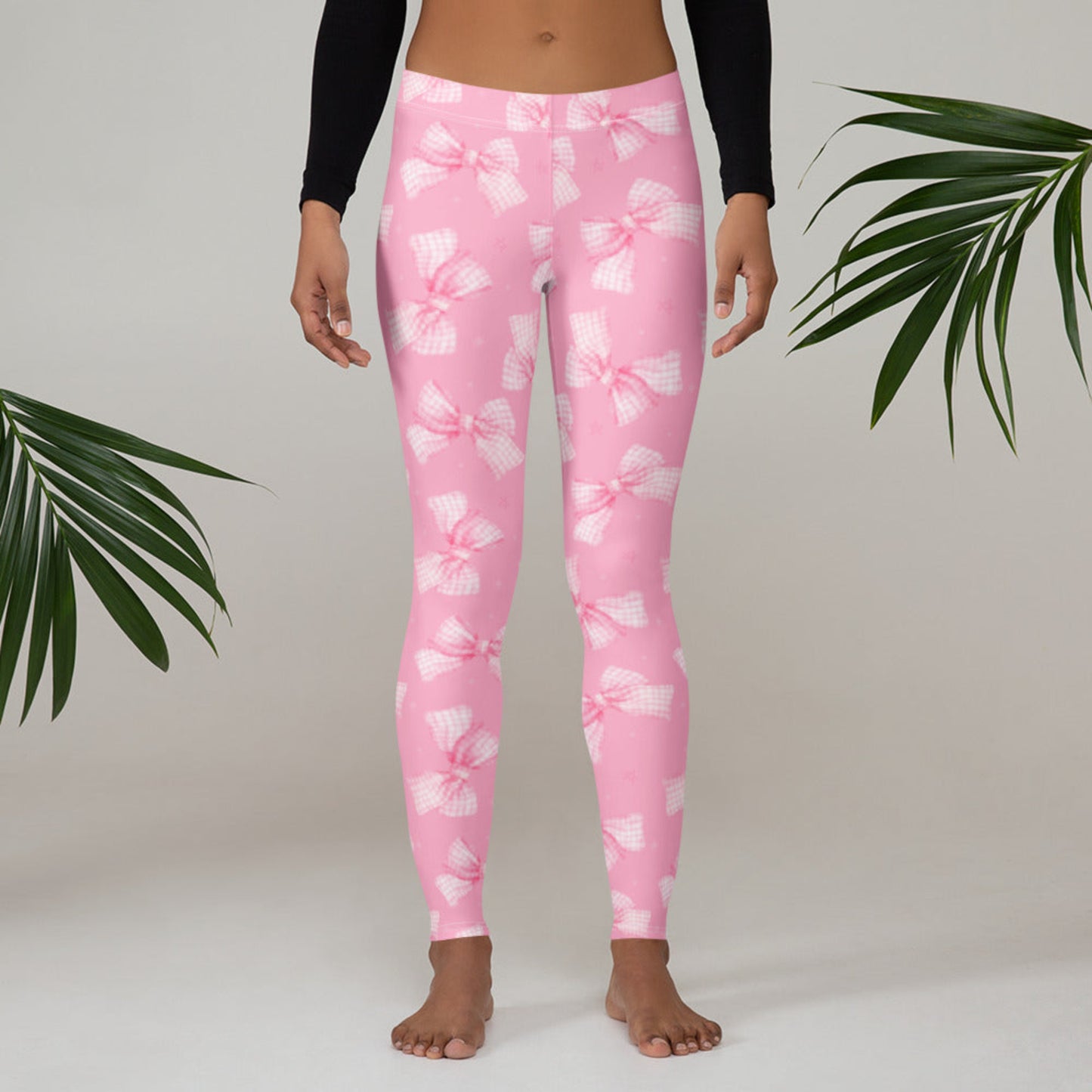 Image: Closeup of women’s pink leggings with all over bow print, highlighting the soft fabric and elastic waistband. These coquette aesthetic leggings are the perfect gift for teens, young women, or moms who love to match with their little ones in cute and cozy clothing, by jaecrece.