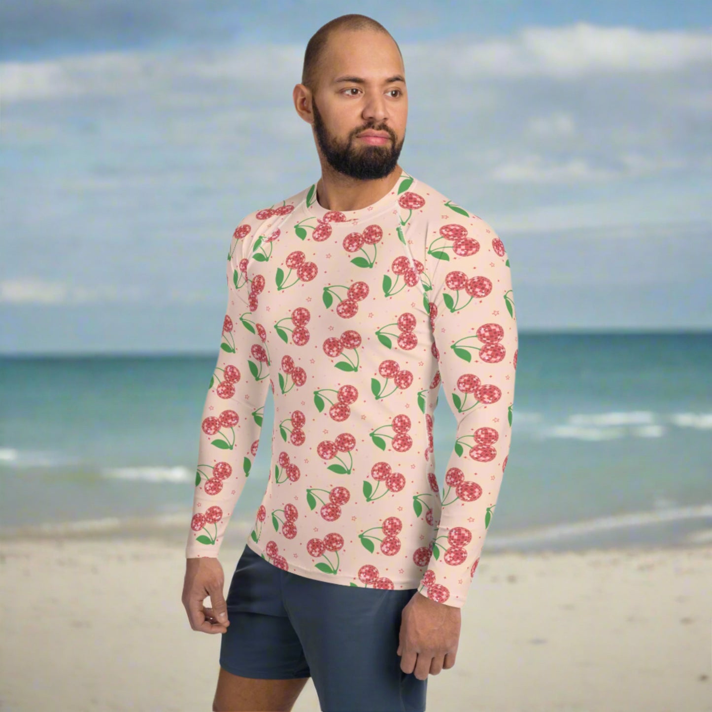 Image: Disco Cherries Mens Rash Guard, part of a family matching swimwear collection. This rash guard has a pink background, with a pattern of red disco ball cherries and stars, by jaecrece