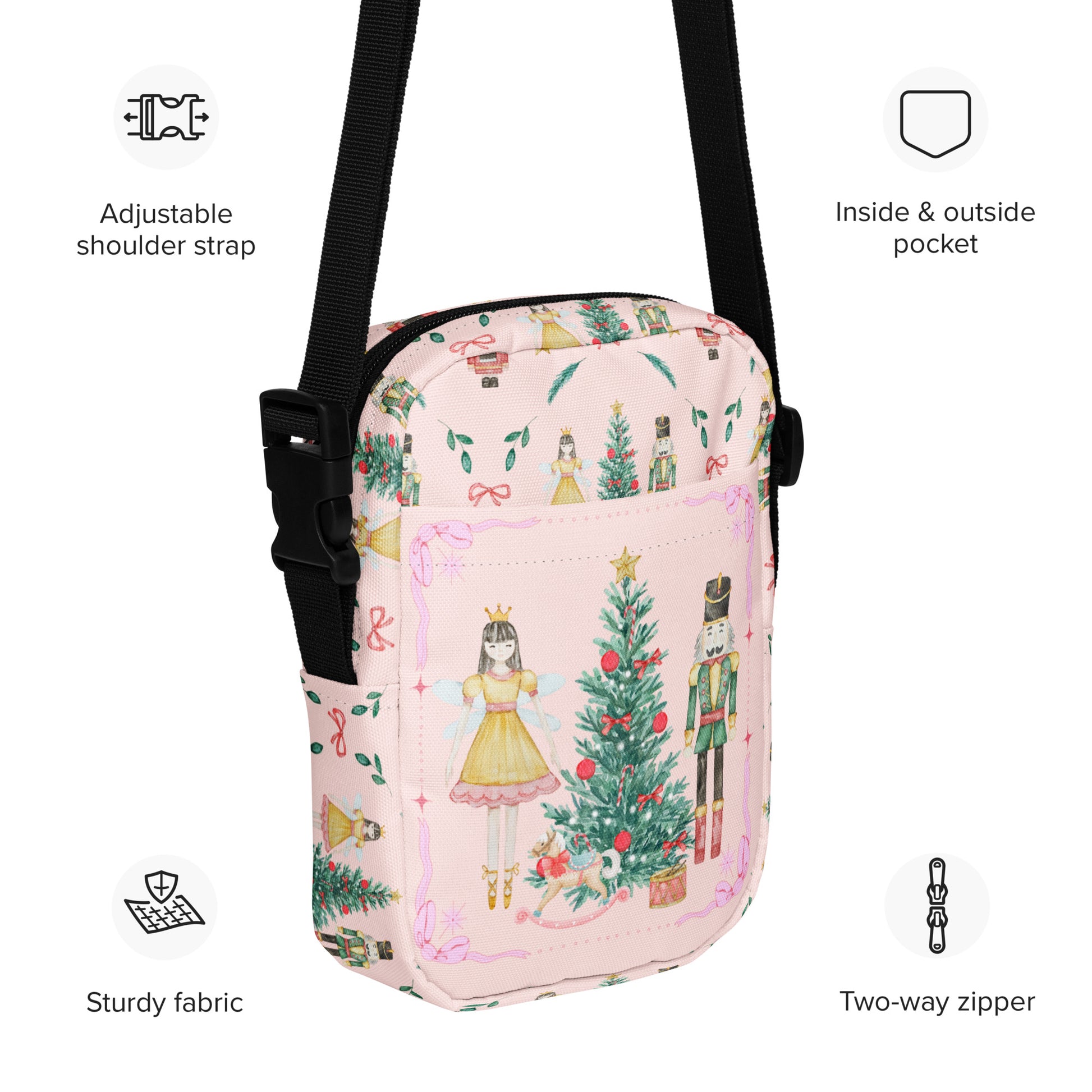 Image: Pink Coquette Nutcracker Utility Crossbody bag. The front of this small mini tote has a Christmas tree, Nutcracker, Sugarplum Fairy, Rocking Horse and a holiday present The rest of the purse is covered in a pattern of ribbons, garland, and Nutcrackers. May be worn across the waist/ hips, across the chest or as a mini backpack, by jaecrece